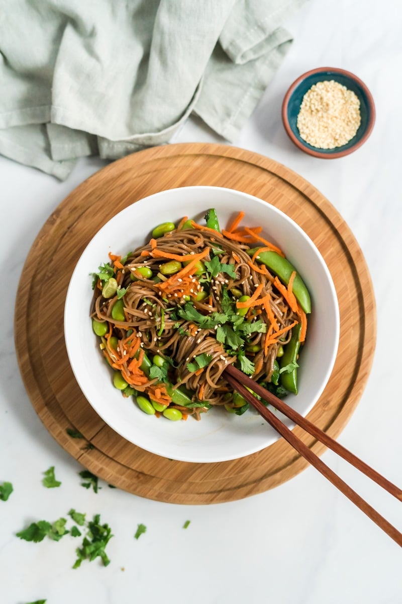 Easy Asian noodle bowl with soba noodles and vegetables served with cilantro and sesame seeds in a bowl with chopsticks.