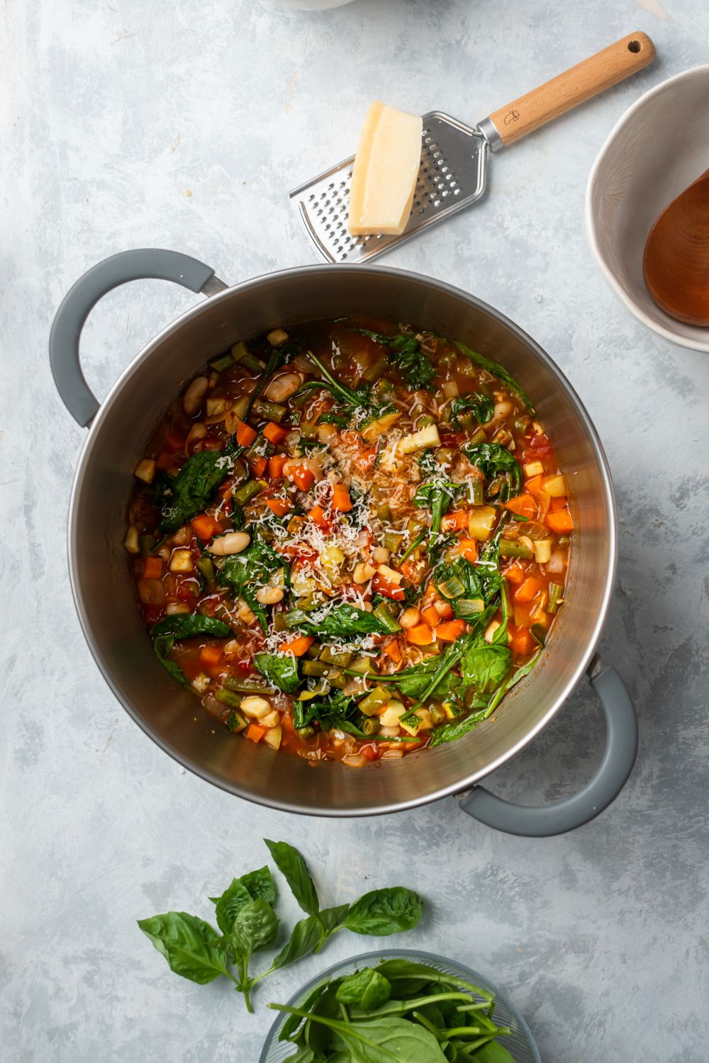 Bean and vegetables soup with Italian flavors in a soup pot with parmesan cheese and basil.