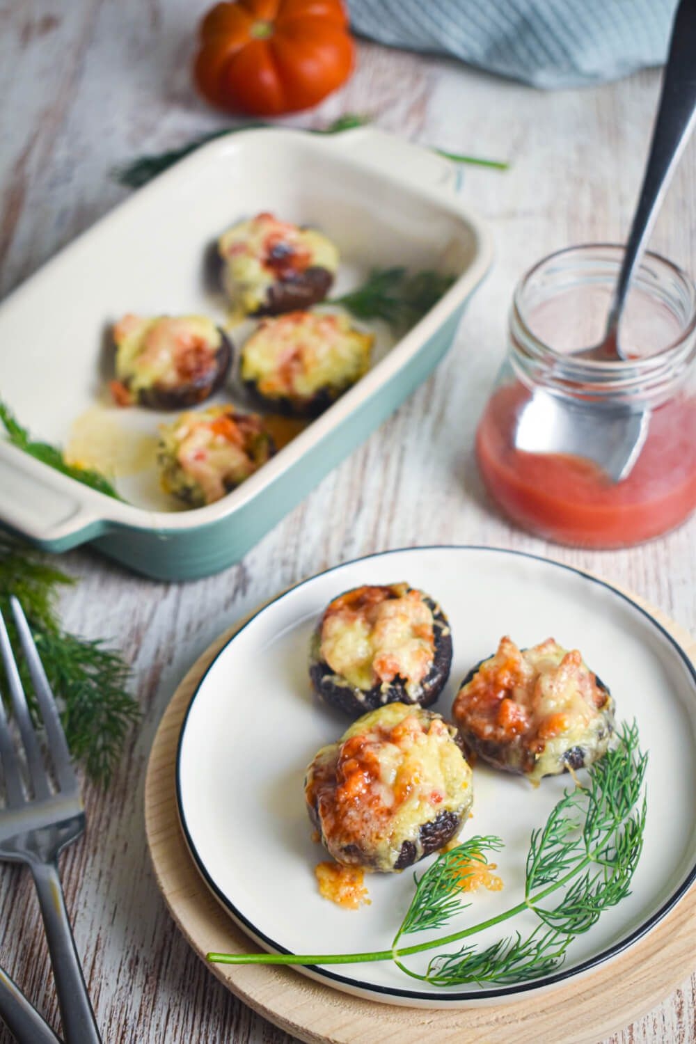 Mexican stuffed mushrooms with melted cheese and enchilada sauce on a plate. 