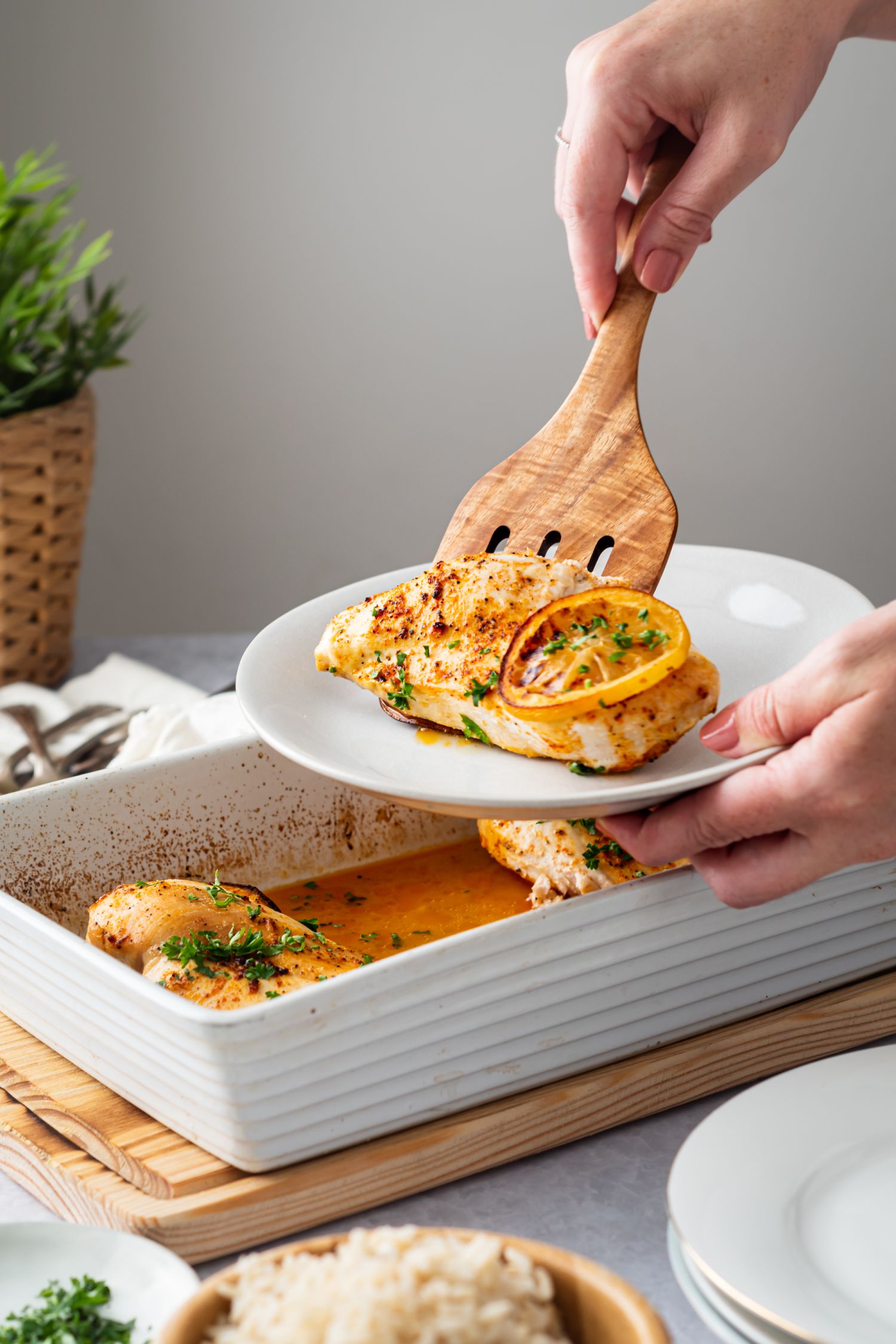 Chicken with lemon pepper seasoning being picked up by a wooden spatula.