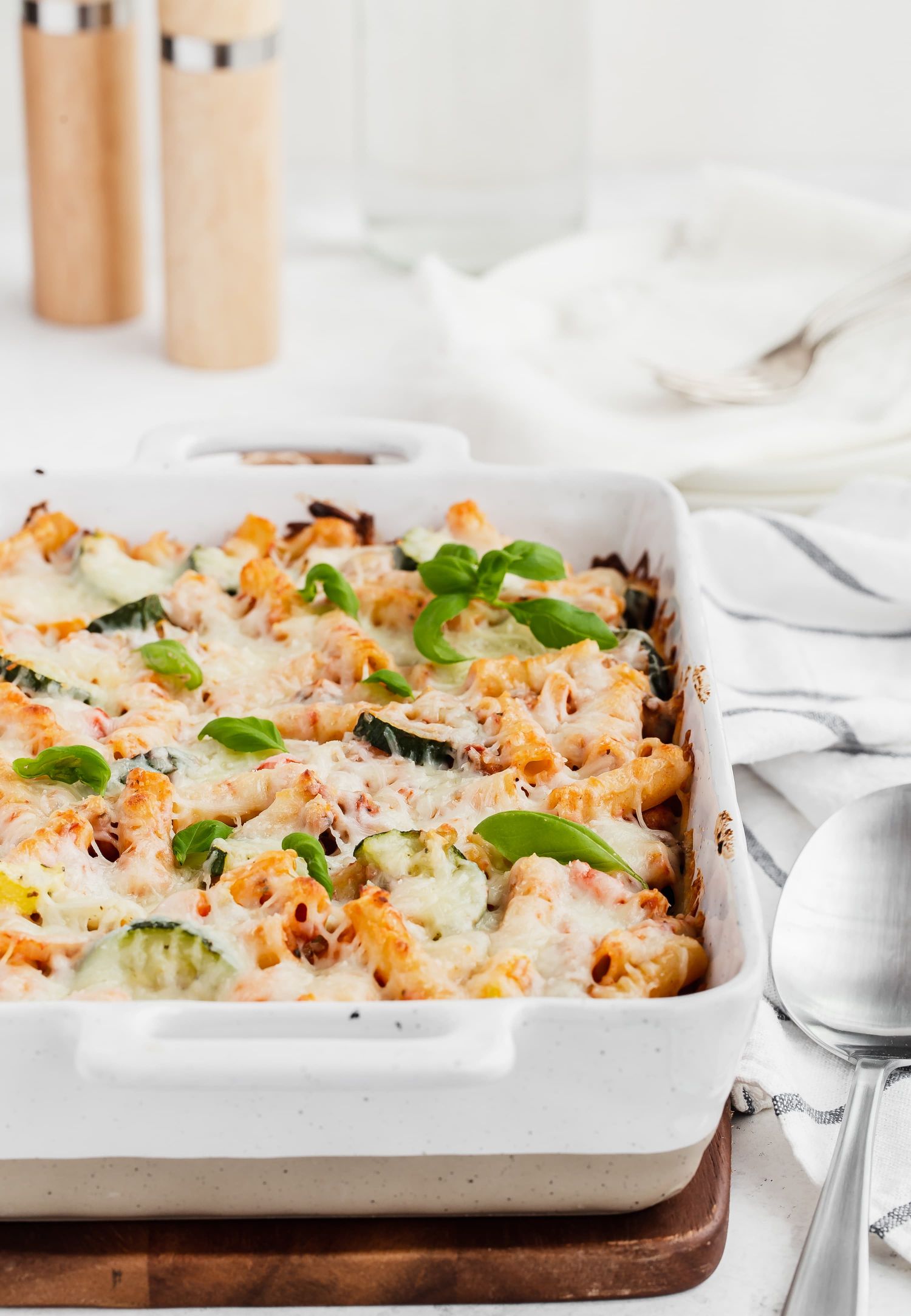 Baked Ziti with roasted vegetables in a casserole dish with cheese melted on top.