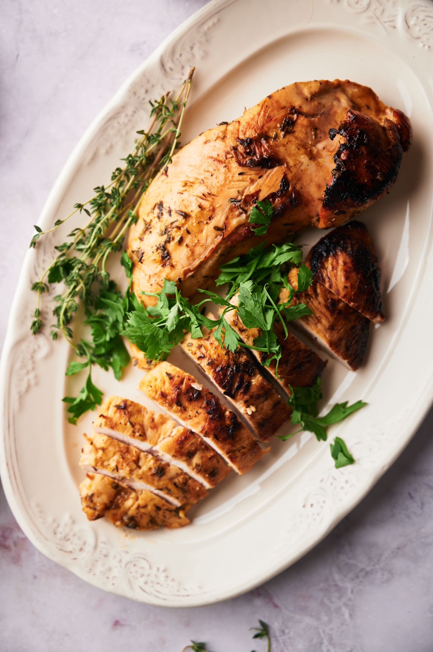 Turkey breast tenderloin baked and served in a platter with parsley and thyme.