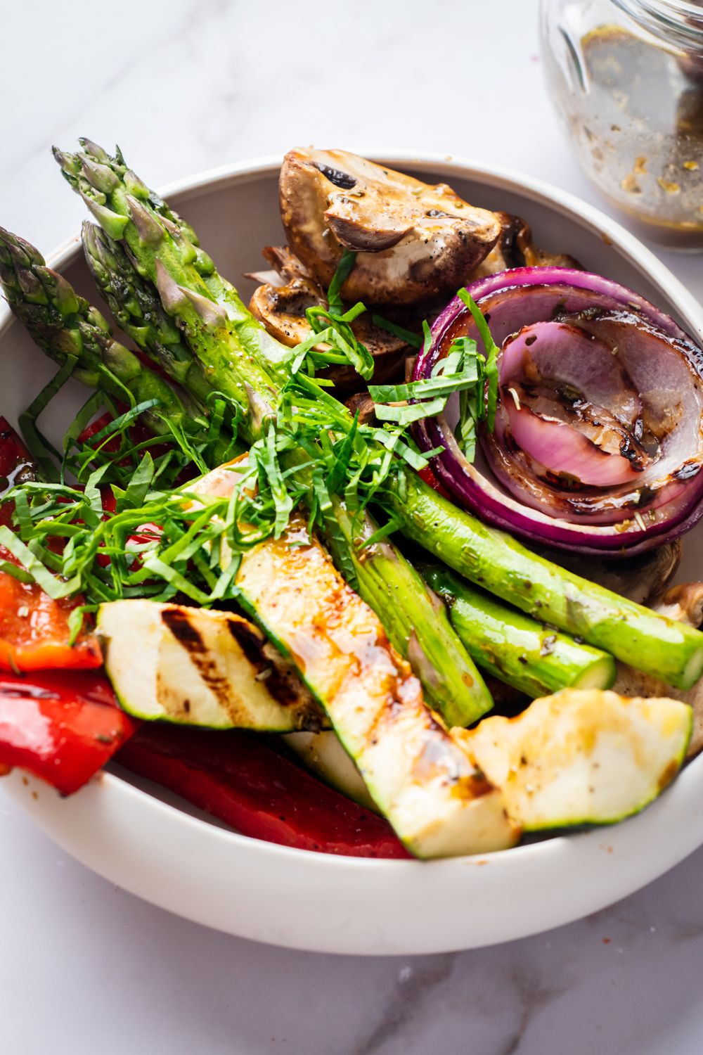 Grilled zucchini, asparagus, red onion, mushrooms, and red peppers in a bowl with balsamic marinade.