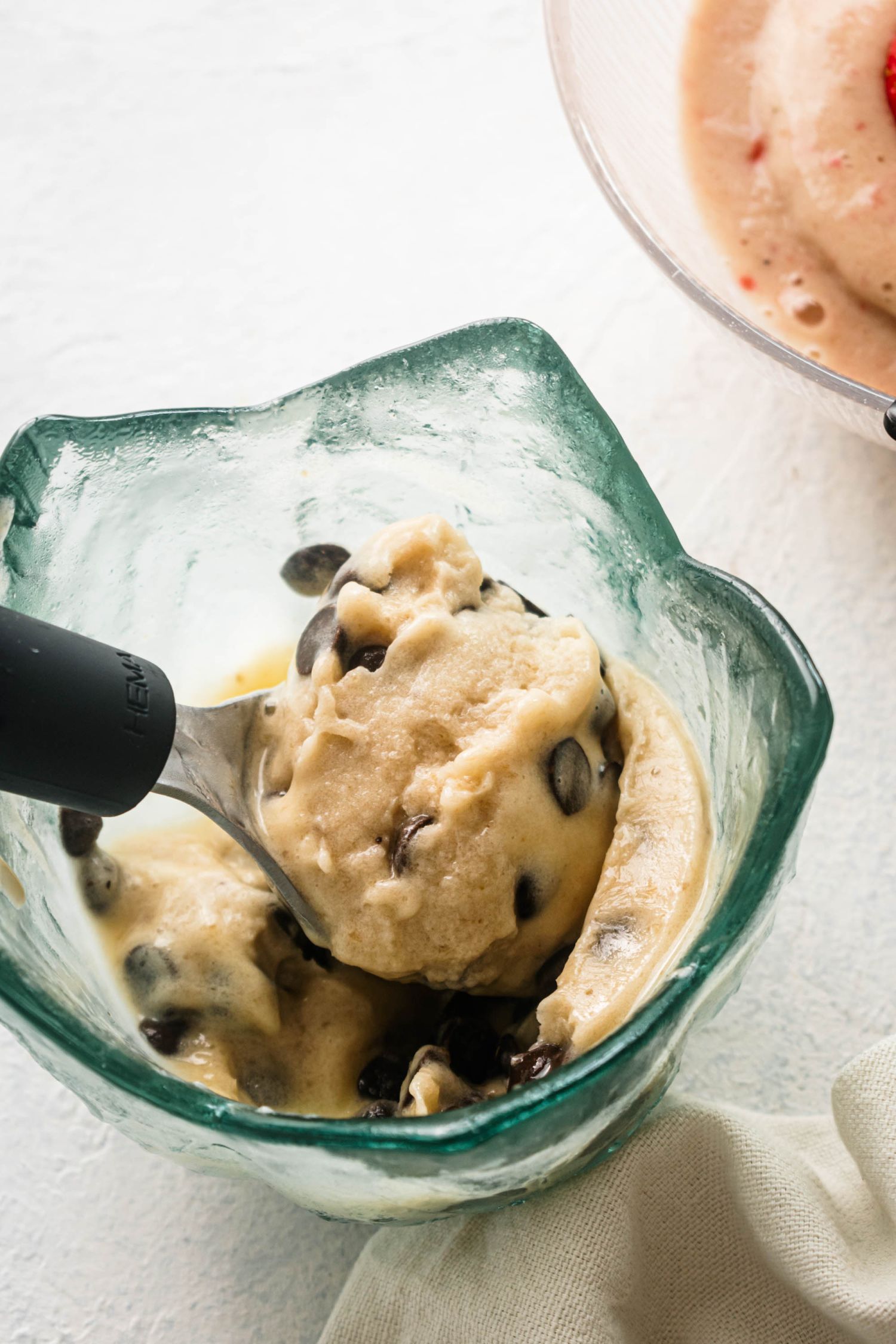 Chocolate chip banana nice cream in an ice cream dish with a scoop.