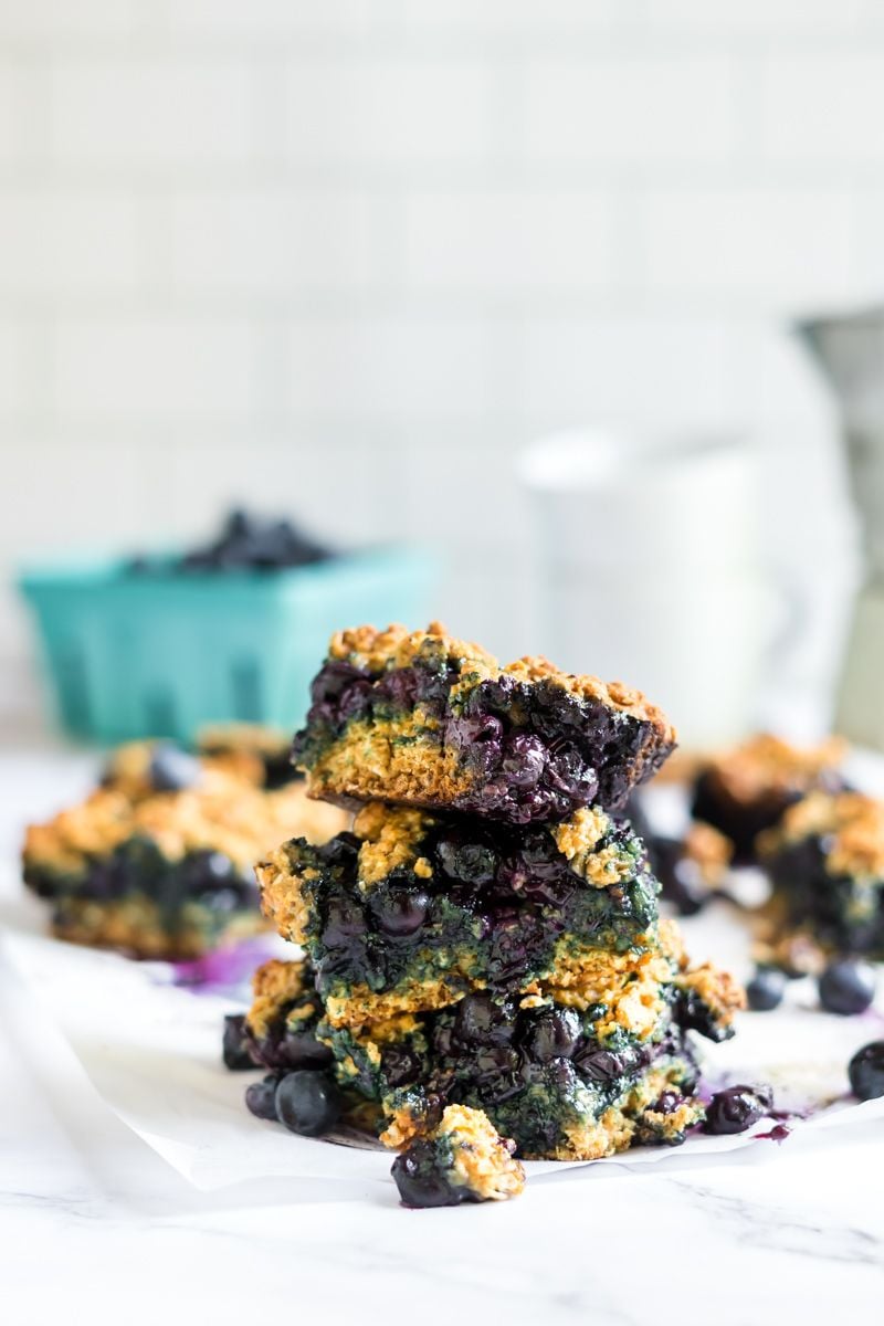 Oatmeal bars with blueberries stacked on each other with fresh blueberries on the side.