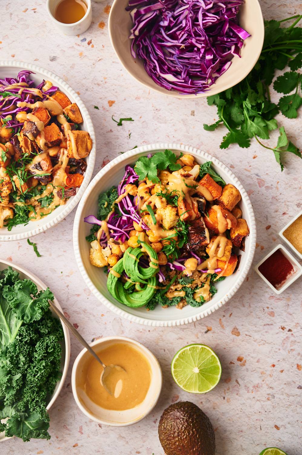 Easy buddha bowl with roasted vegetables, kale, quinoa, and avocado in two bowls.