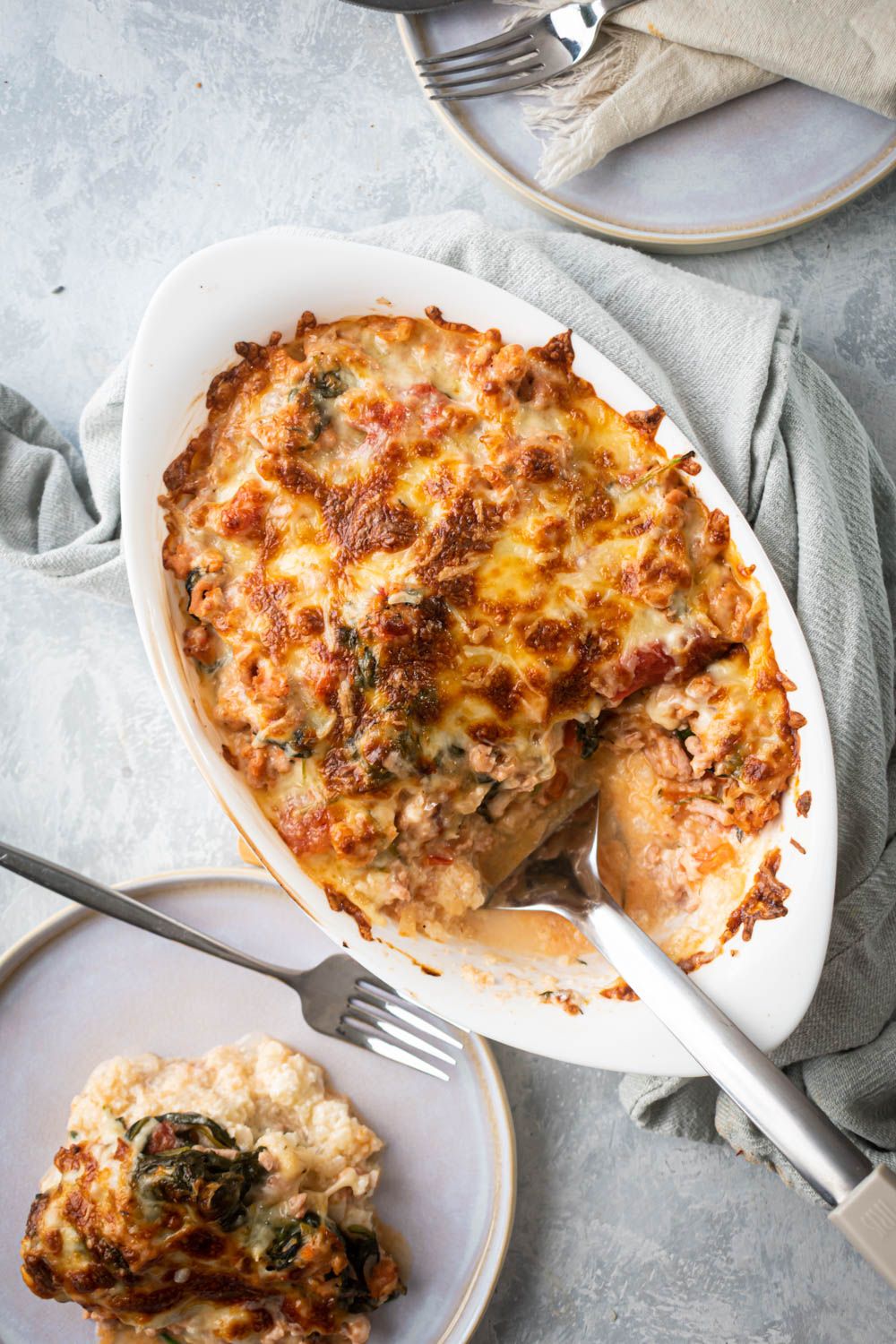 Low carb cauliflower rice and turkey casserole topped with melted cheese and served on a plate.