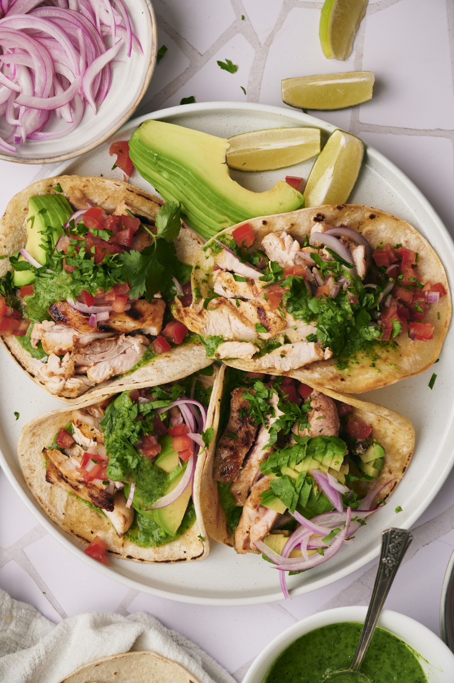 Grilled chicken street tacos served in corn tortillas with cilantro, onion, salsa, lime, and avocado.