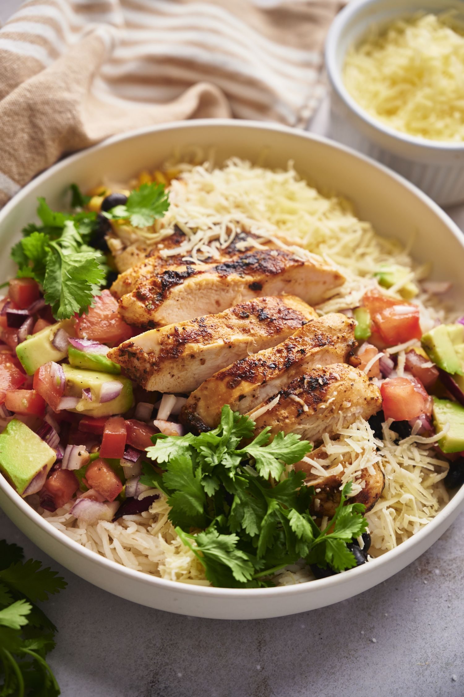 Chicken taco bowls with cooked rice, black beans, cilantro, tomatoes, avocado, and red onion.