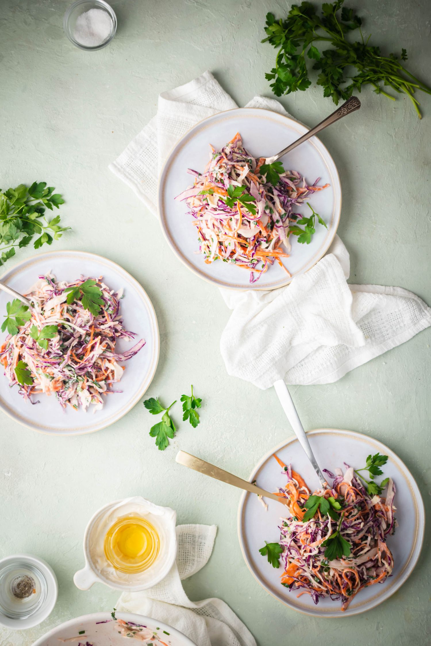 Cabbage and carrot coleslaw with Greek yogurt and fresh herbs on three white plates. 