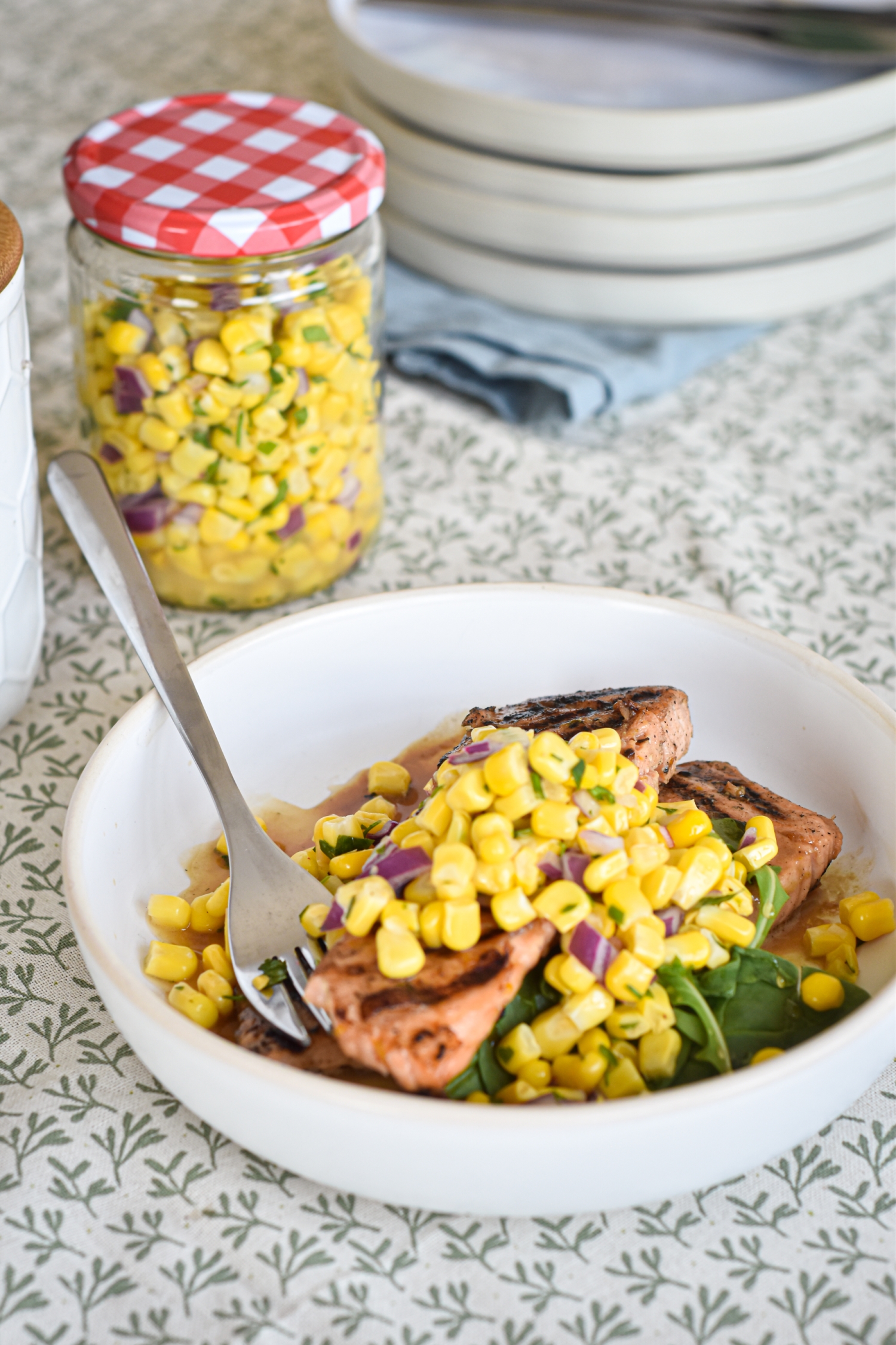 Bowl with corn salsa served over grilled salmon with extra corn salsa on the side. 