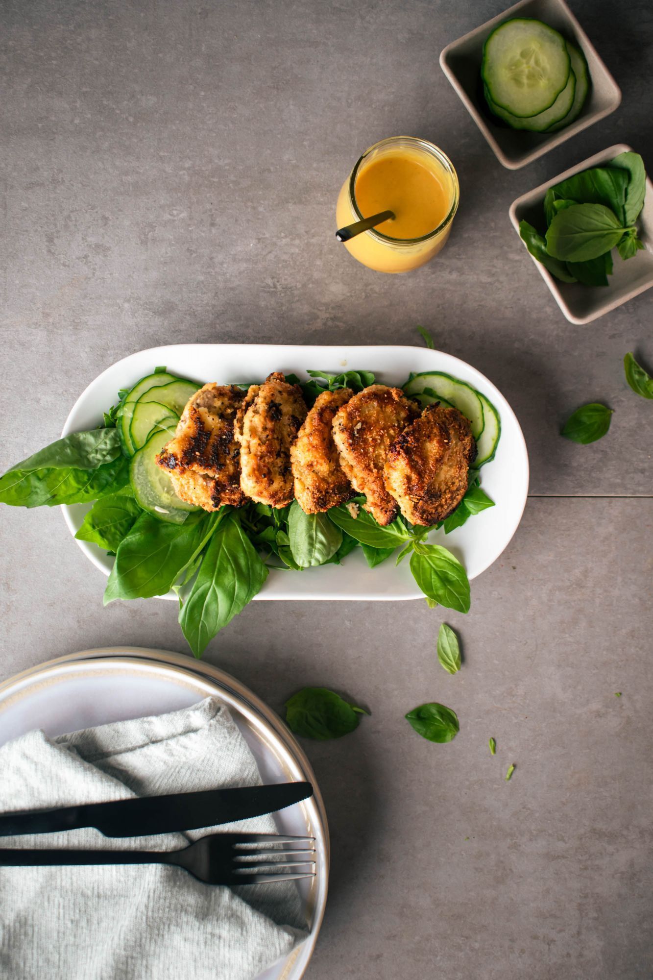 Pork chops with almond meal breading cooked until crispy and served on a plate with greens and cucumbers.