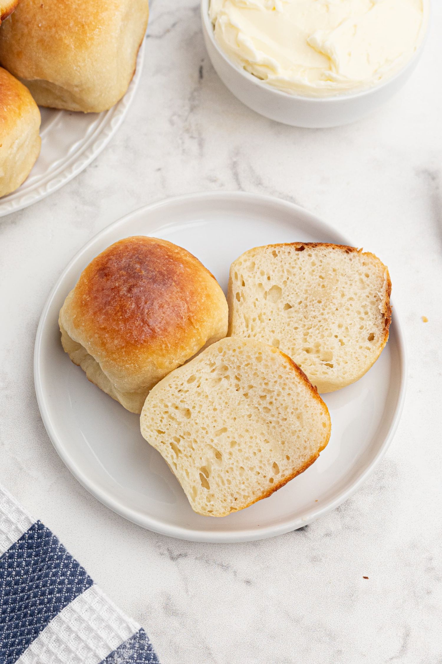 Greek yogurt dough dinner rolls served in a plate and cut in half with butter on the side.