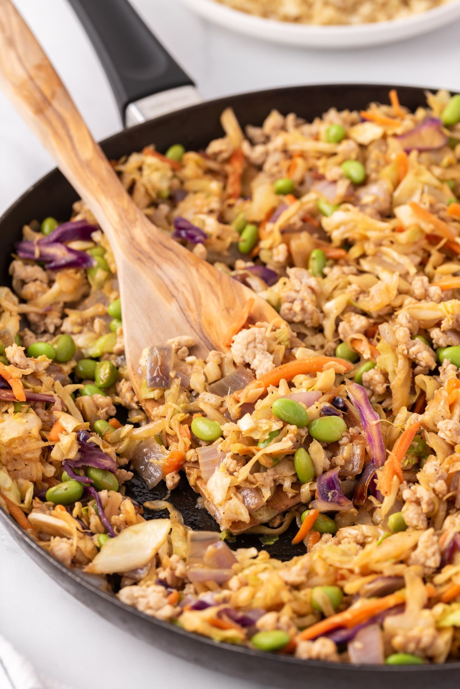 Skillet with egg roll in a bowl made with ground chicken, cabbage slaw, and edamame. 