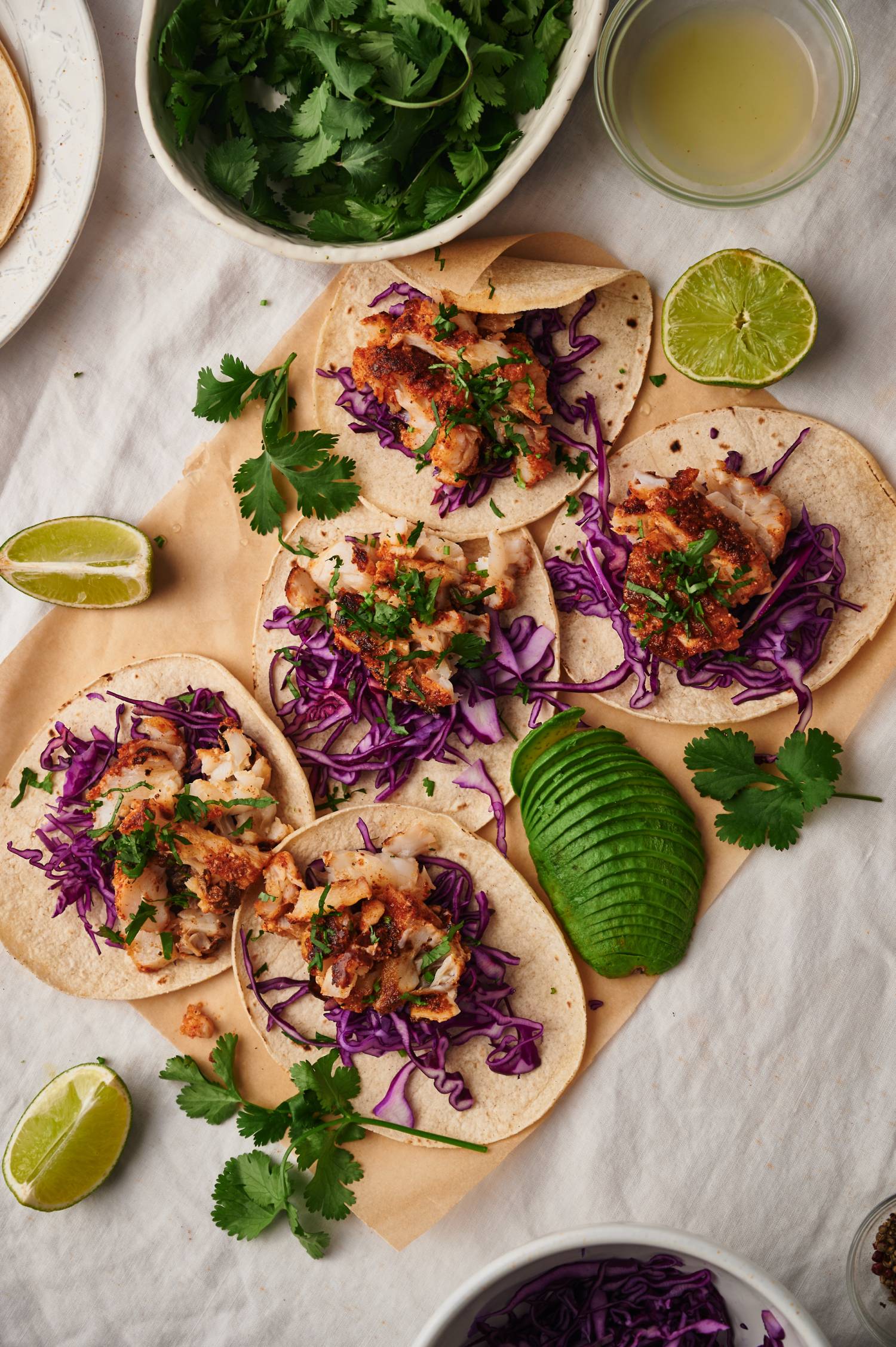 Traditional fish tacos with homemade spice rub, cabbage, cilantro, lime, and avocado served on totrillas.