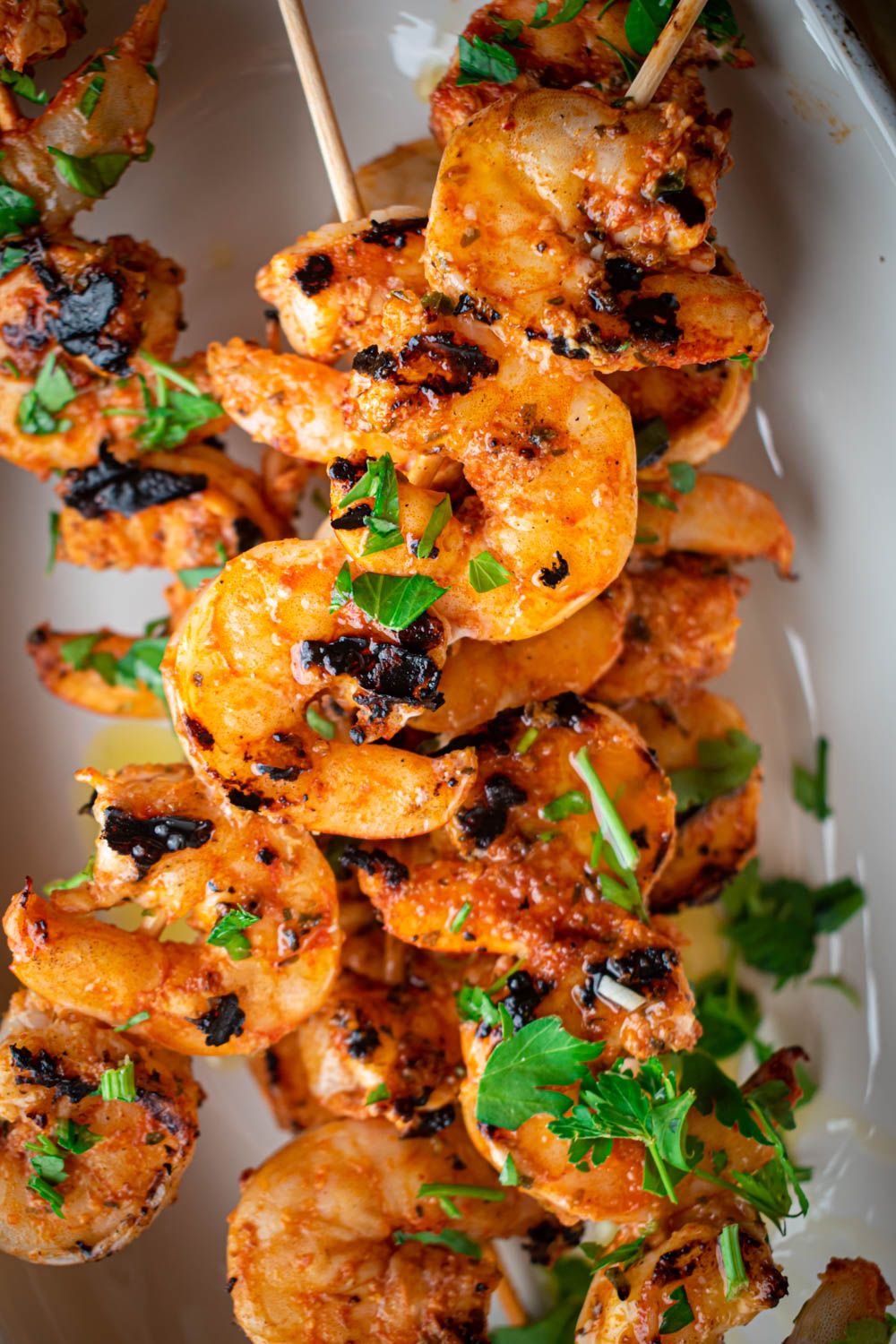 Grilled shrimp kabobs with spices, olive oil, lemon juice, and parsley on wooden skewers.