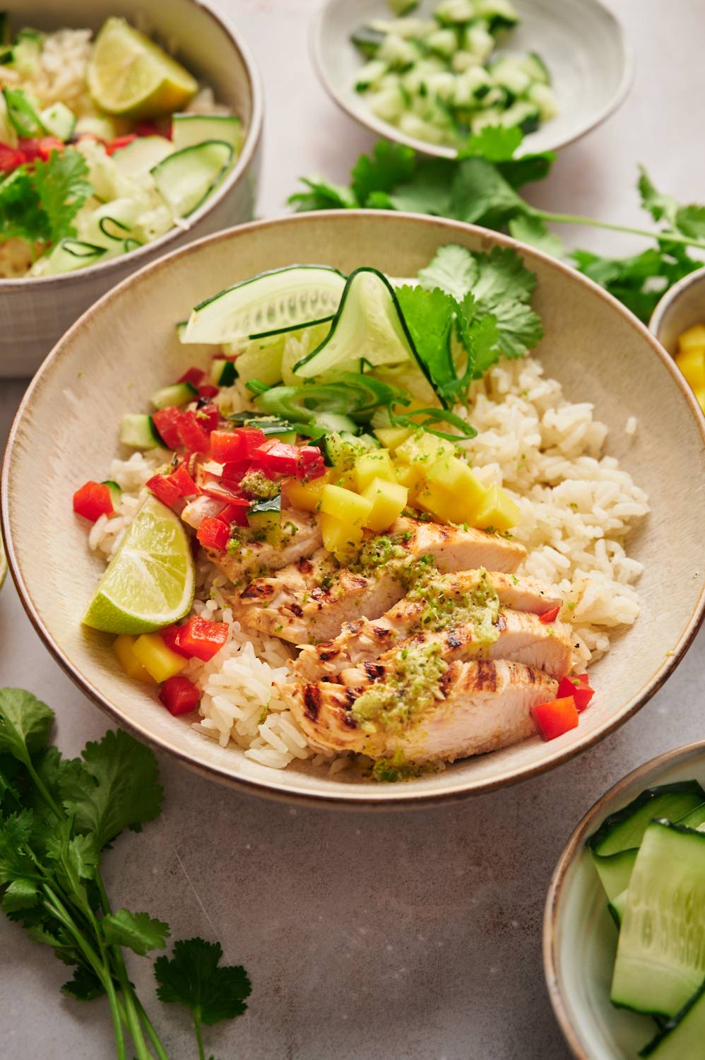 Grilled chicken and mango salsa bowls with white rice, cilantro, and limes in a white bowl.