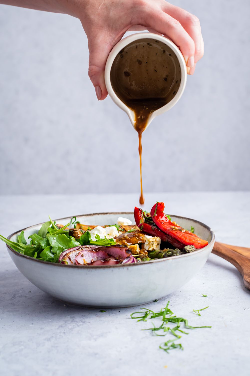 Balsamic dressing being poured on a grilled vegetable salad.