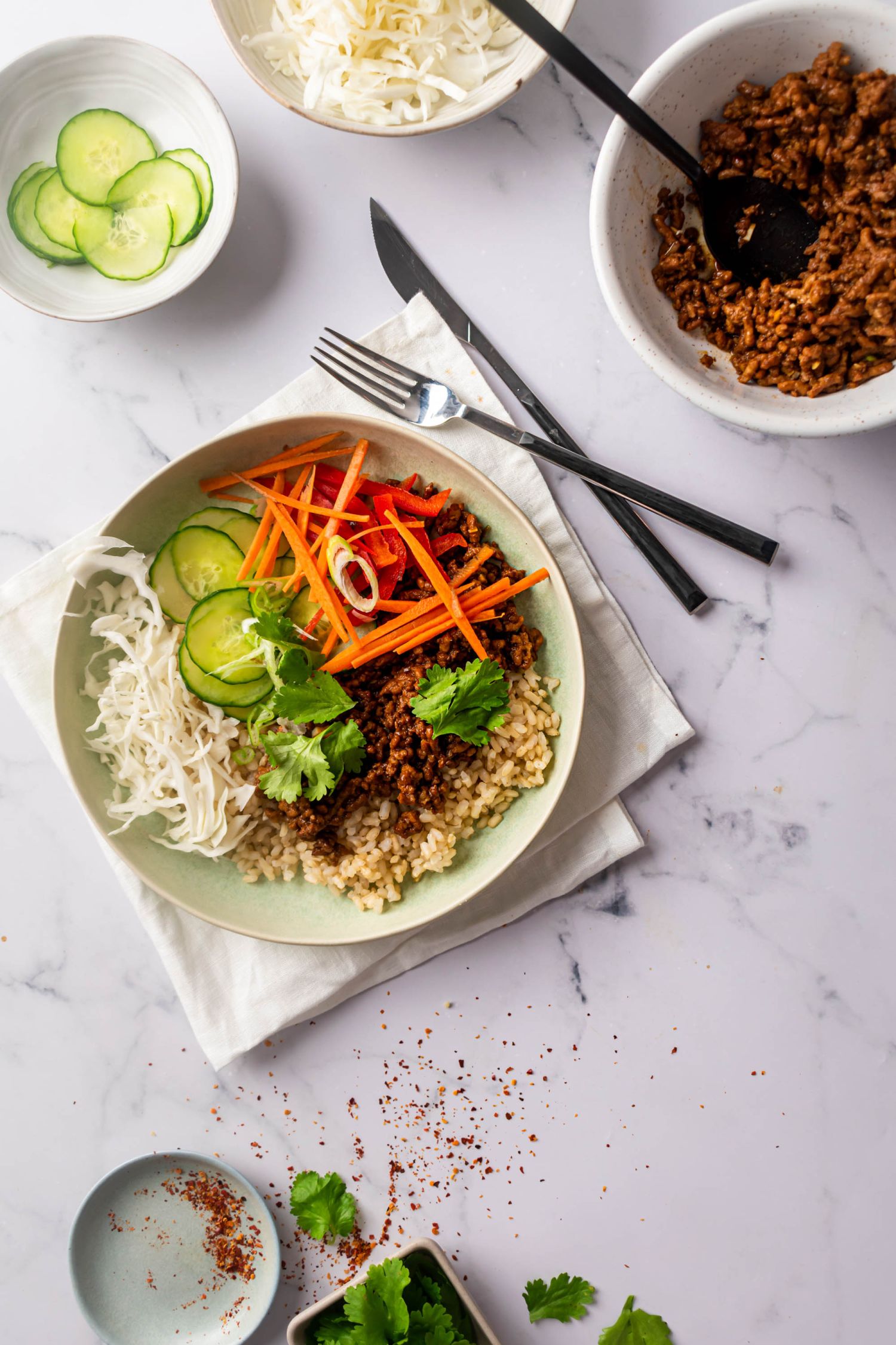 Easy ground beef Bulgogi bowls served with rice and raw vegetables with cucumbers and ground beef on the side.