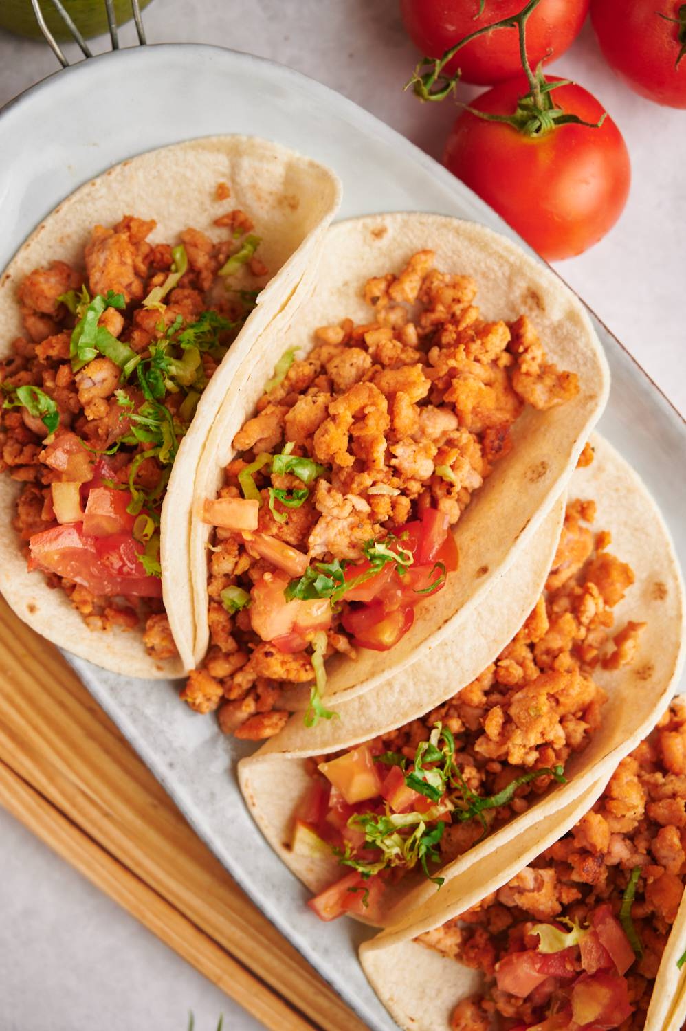 Ground meat tacos with chicken, taco seasoning, tomatoes, and lettuce in corn tortillas.