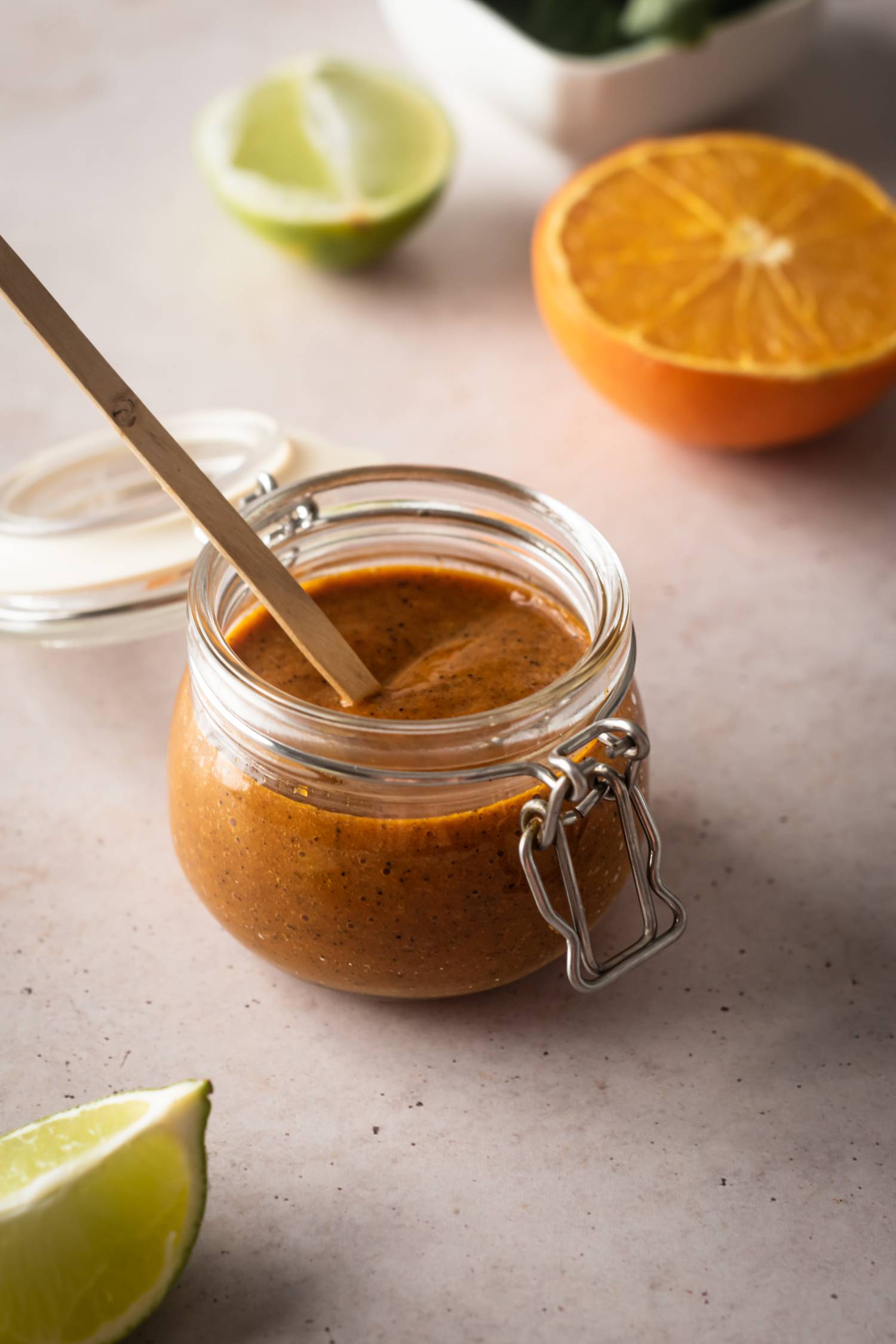 Mexican habanero salsa with lime juice, orange juice, garlic, and tomatoes in a jar with lime and orange on the side.