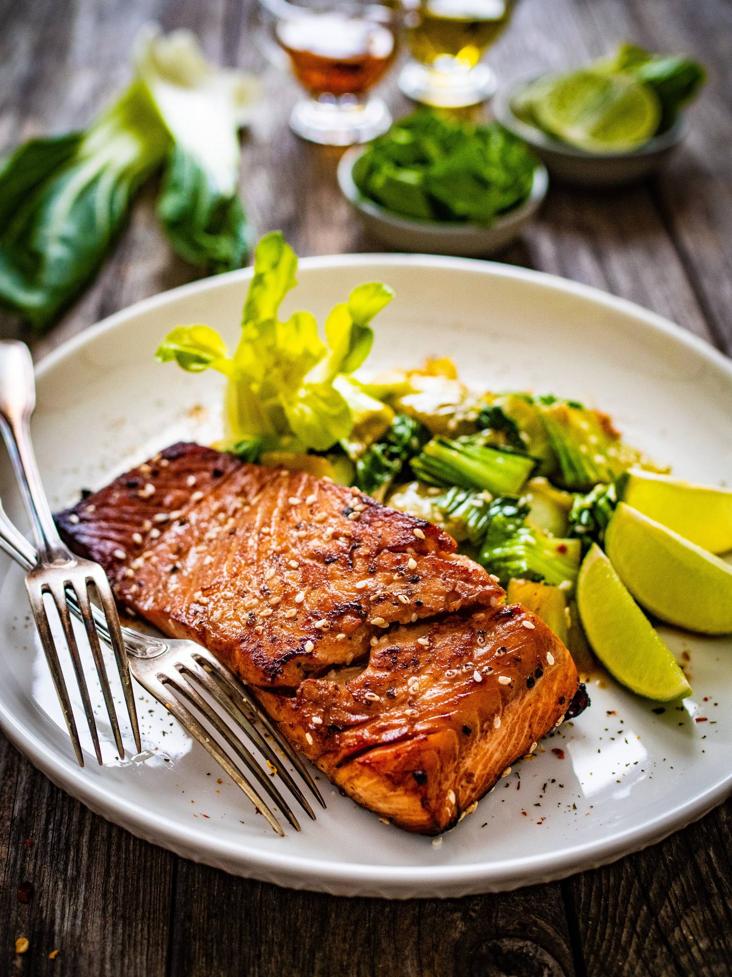 Asian salmon with hoisin sauce served on a white plate with bok choy.