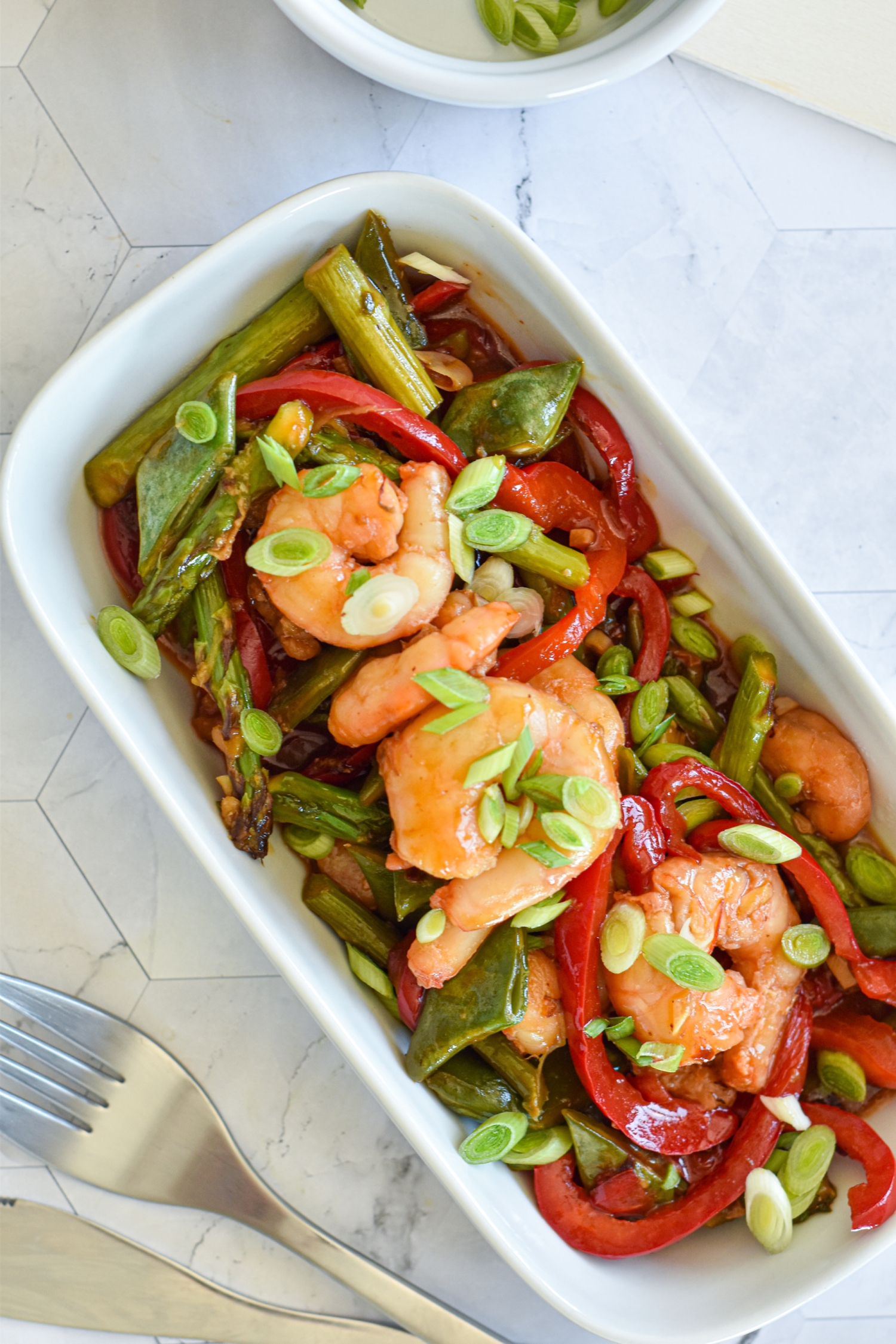 Honey shrimp stir fry with fresh vegetables in a white bowl.