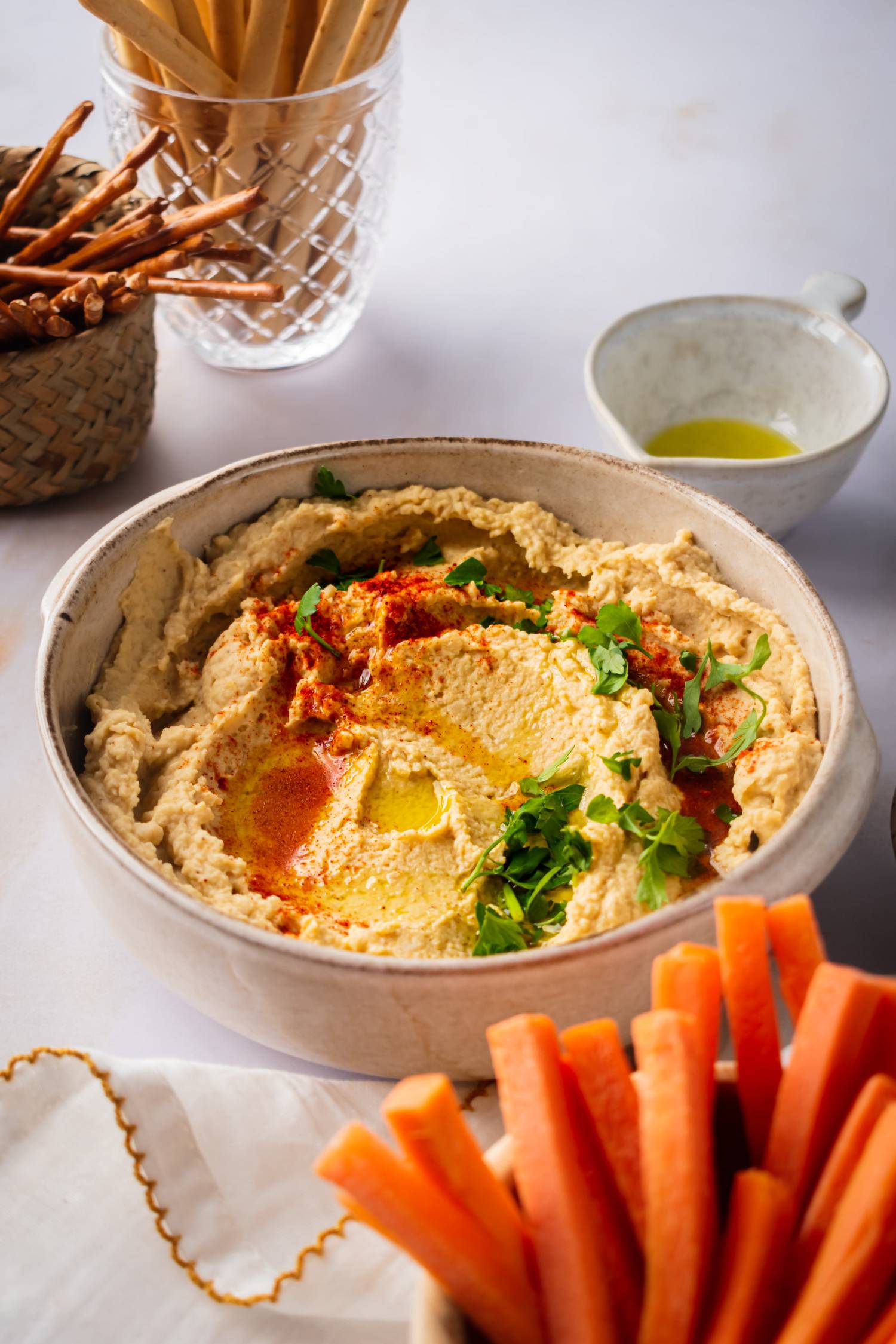 Homemade chickpea hummus in a bowl served with carrots and pretzels.