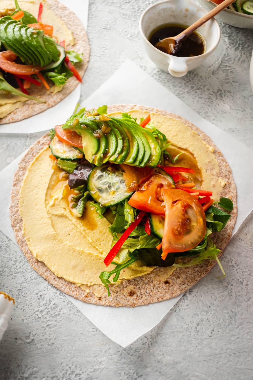 Hummus and vegetable wrap on a whole grain wrap with hummus, tomatoes, avocado, cucumbers, and balsamic vinaigrette.