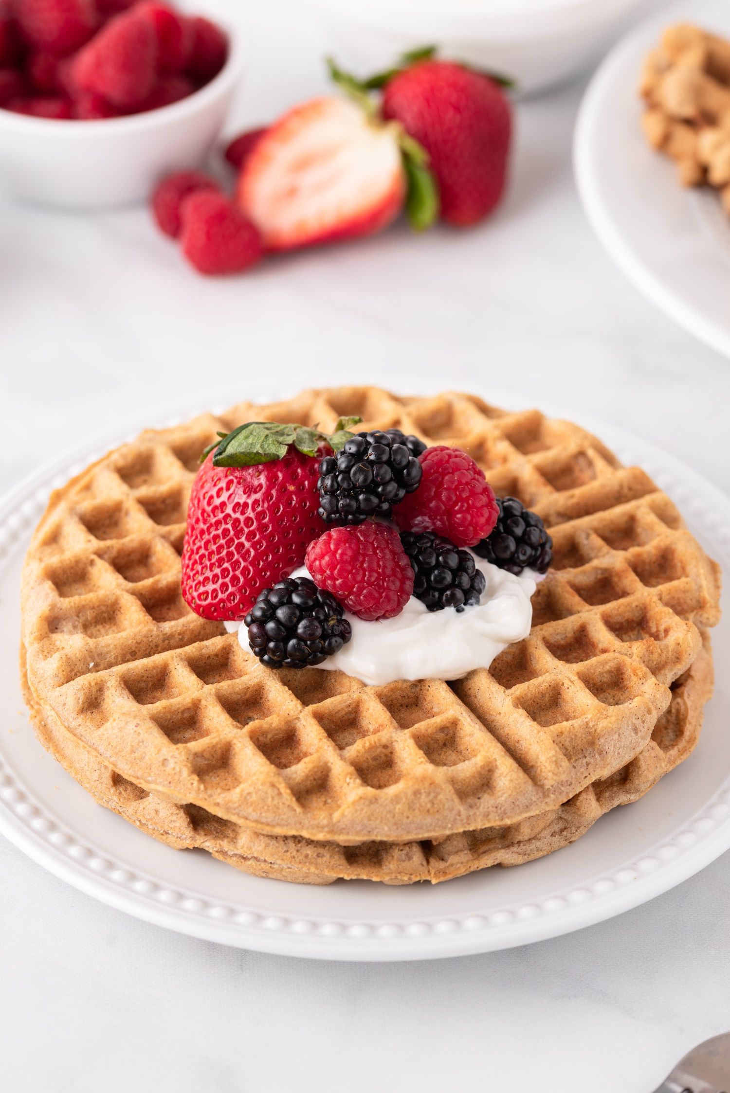 Keto and low carb waffles made with almond flour on a plate with berries and yogurt.