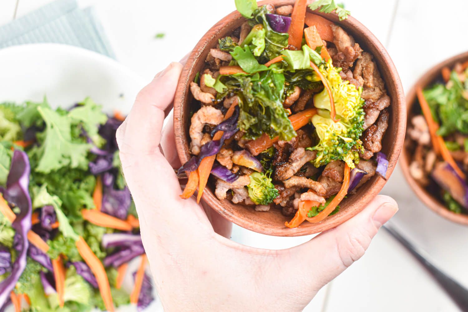 Asian ground turkey and vegetable stir fry with carrots, kale, broccoli, and ground turkey in a wooden bowl.