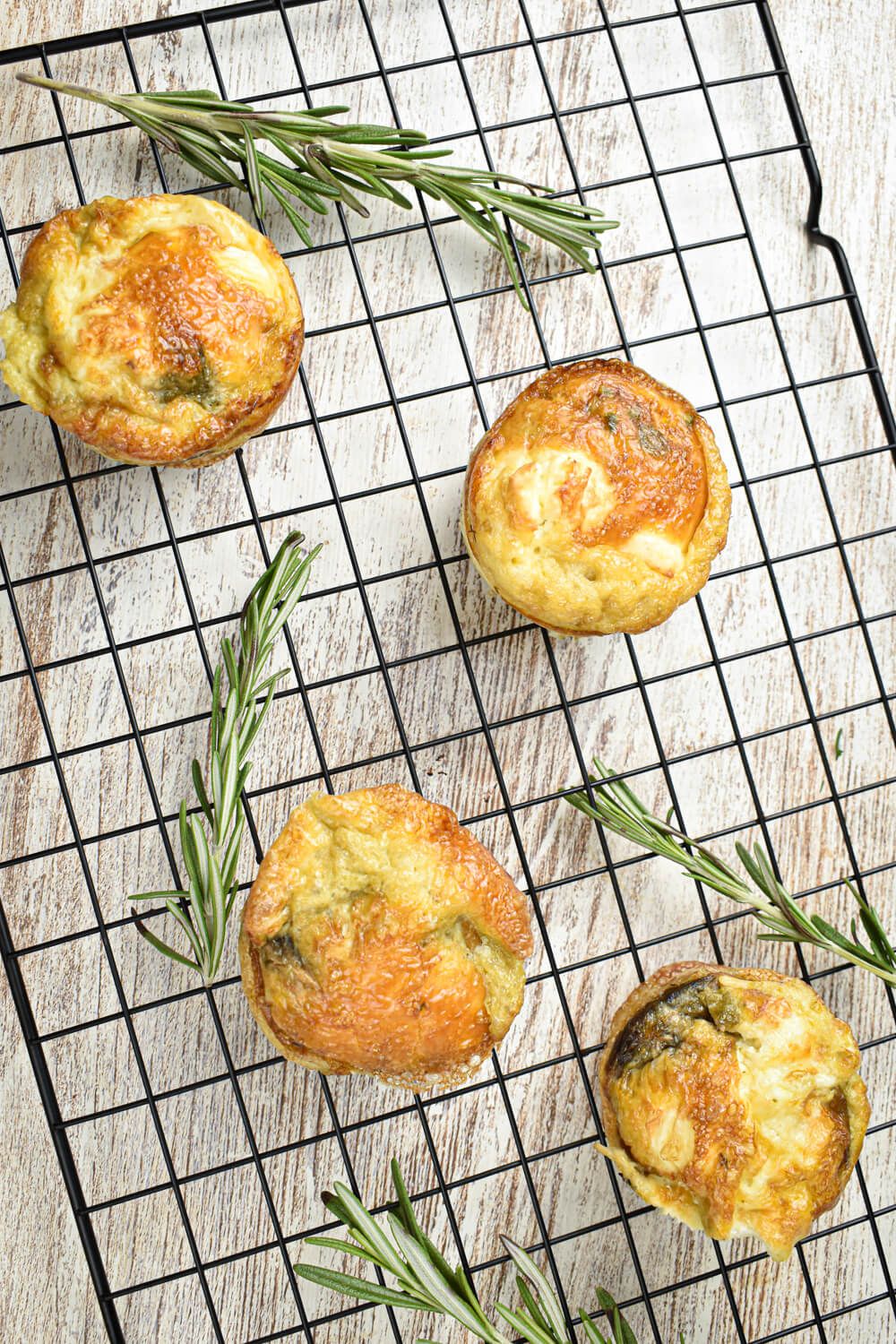 Asparagus mushrooms and feta frittatas on a baking grid with rosemary.