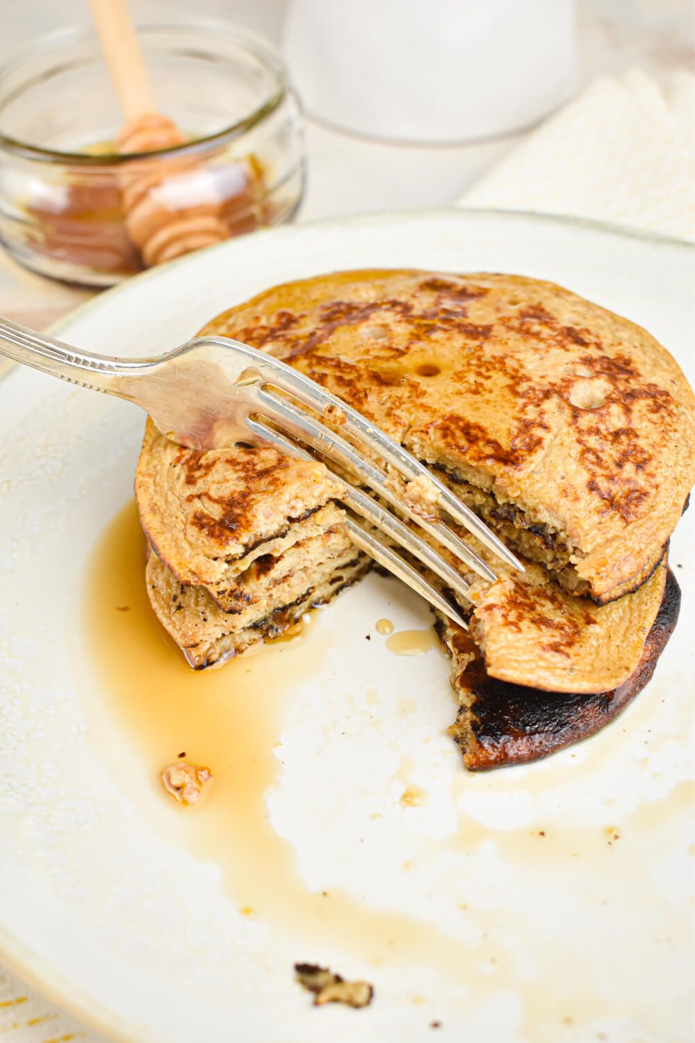 Flax banana pancakes with syrup and a bite taken out with a fork.