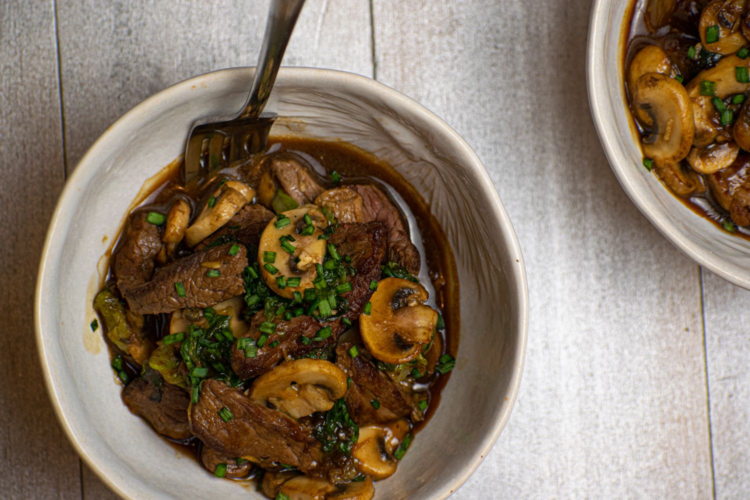 Stir Fry with beef, bok choy, and mushrooms in a bowl with sauce.