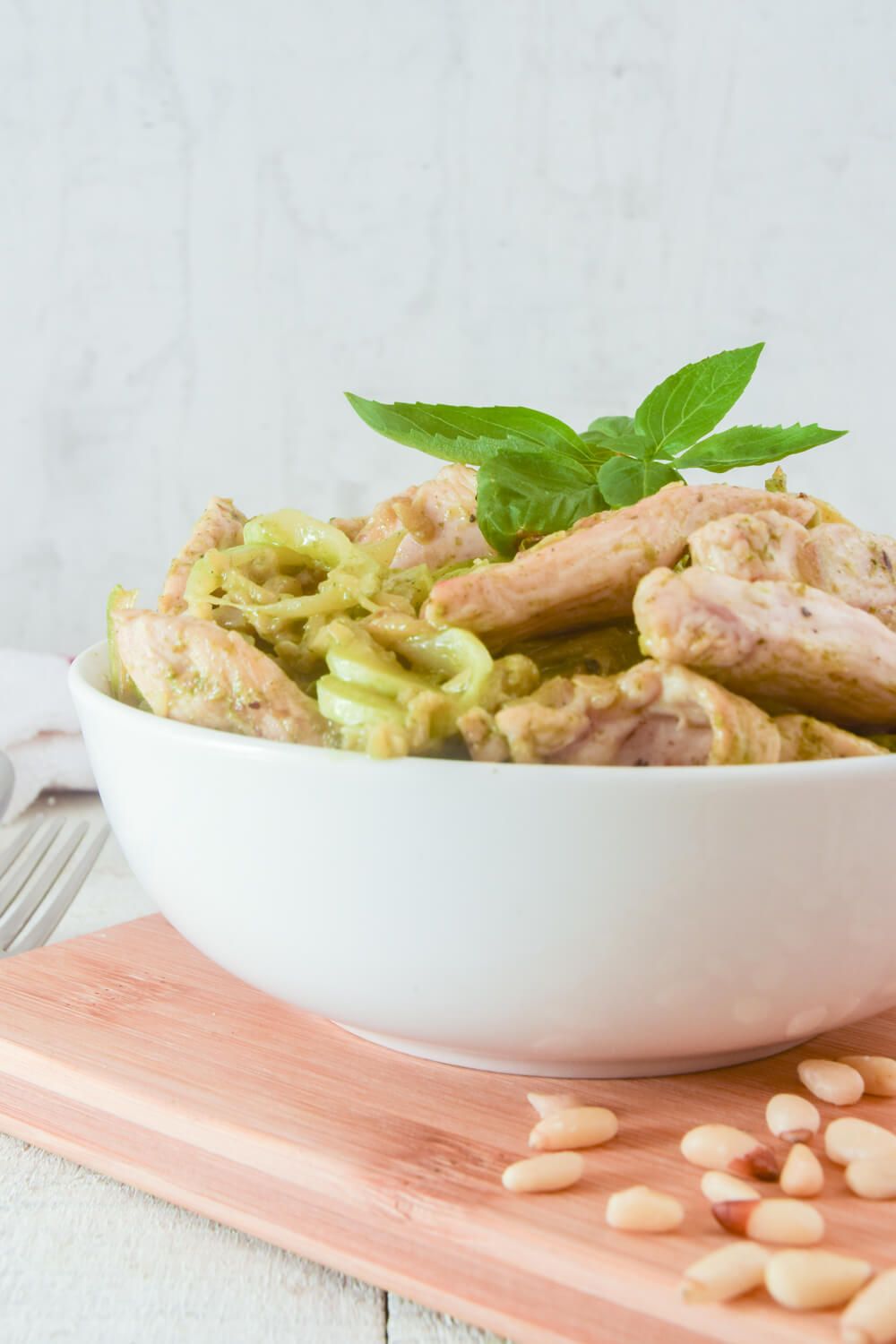 Pesto zucchini noodles with chicken in a creamy sauce in a bowl.