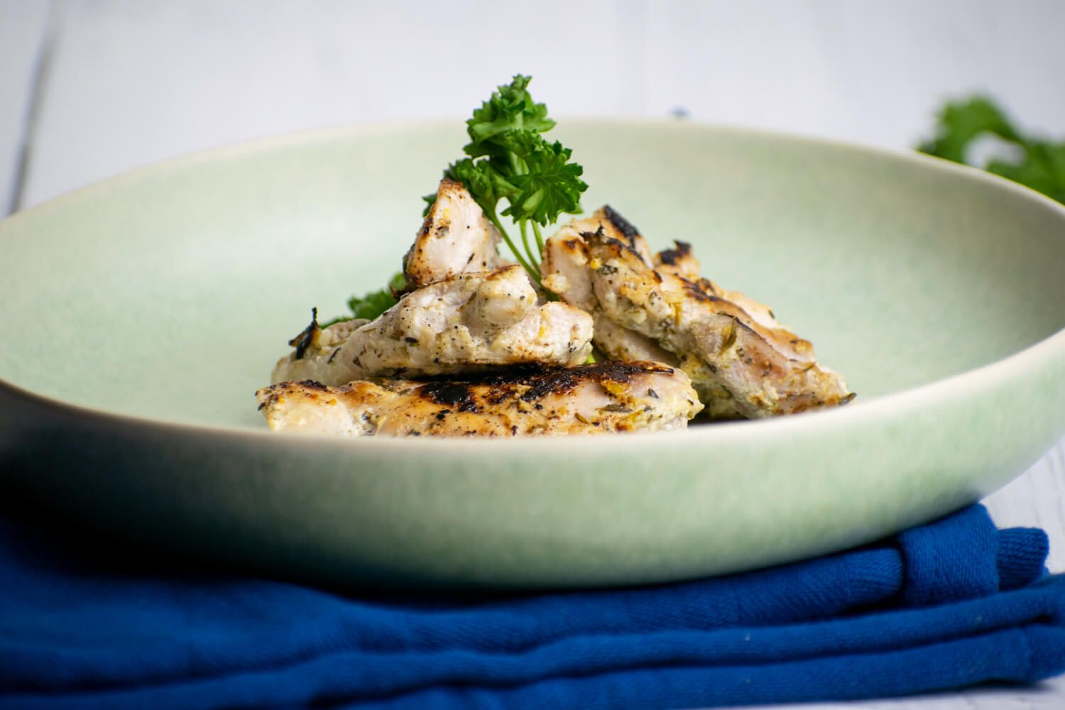 Greek chicken with garlic, lemon, and herbs that is grilled and served with parsley.