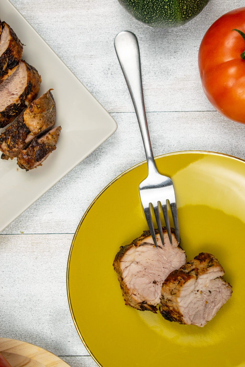 Sliced grilled pork tenderloin with spice rub on a plate with a fork.