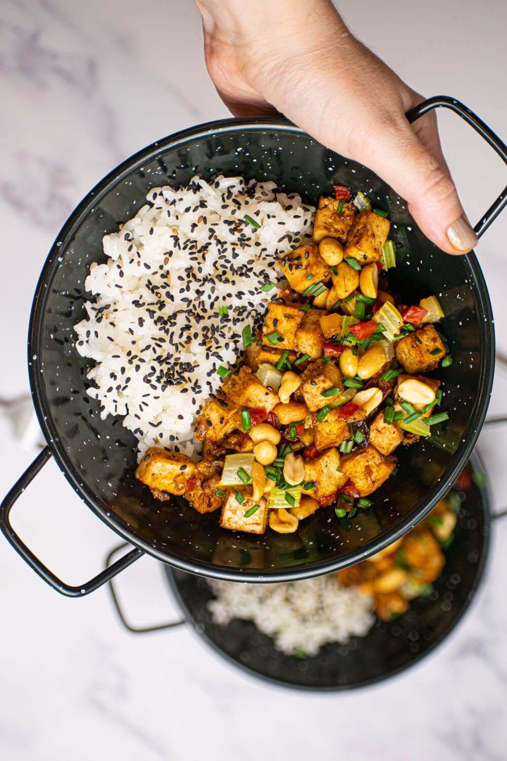 Chinese Kung Pao Tofu with peanuts, red peppers, and celery in a bowl with rice.