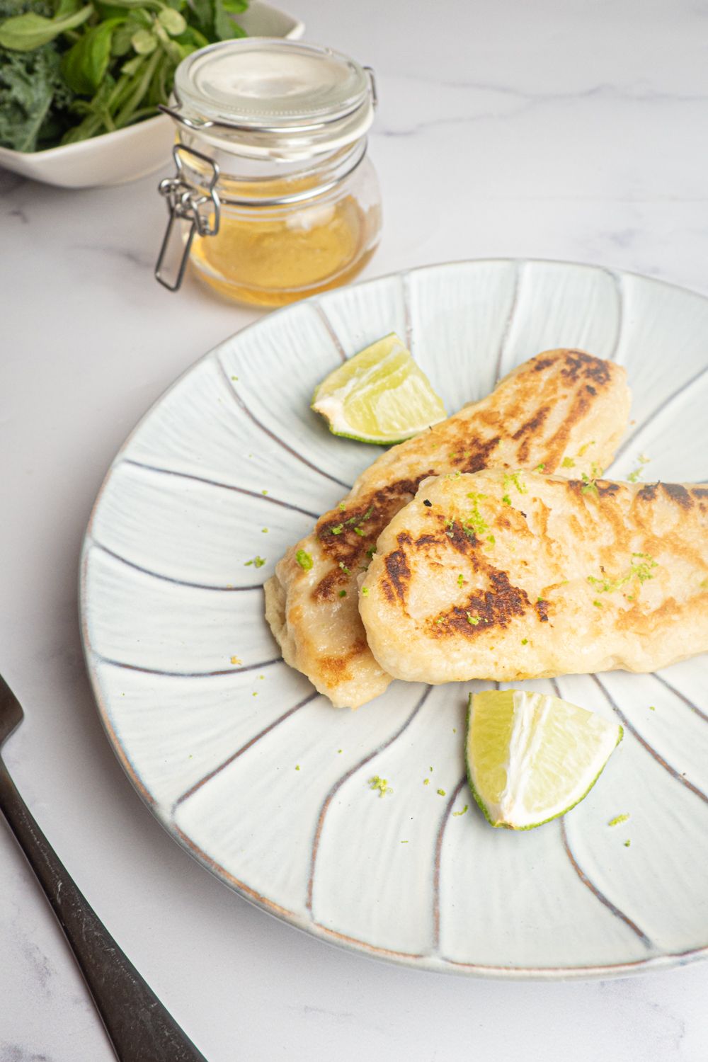 Honey Lime Tilapia with a crispy coating and flavored with honey and lime zest on a plate with a fork.