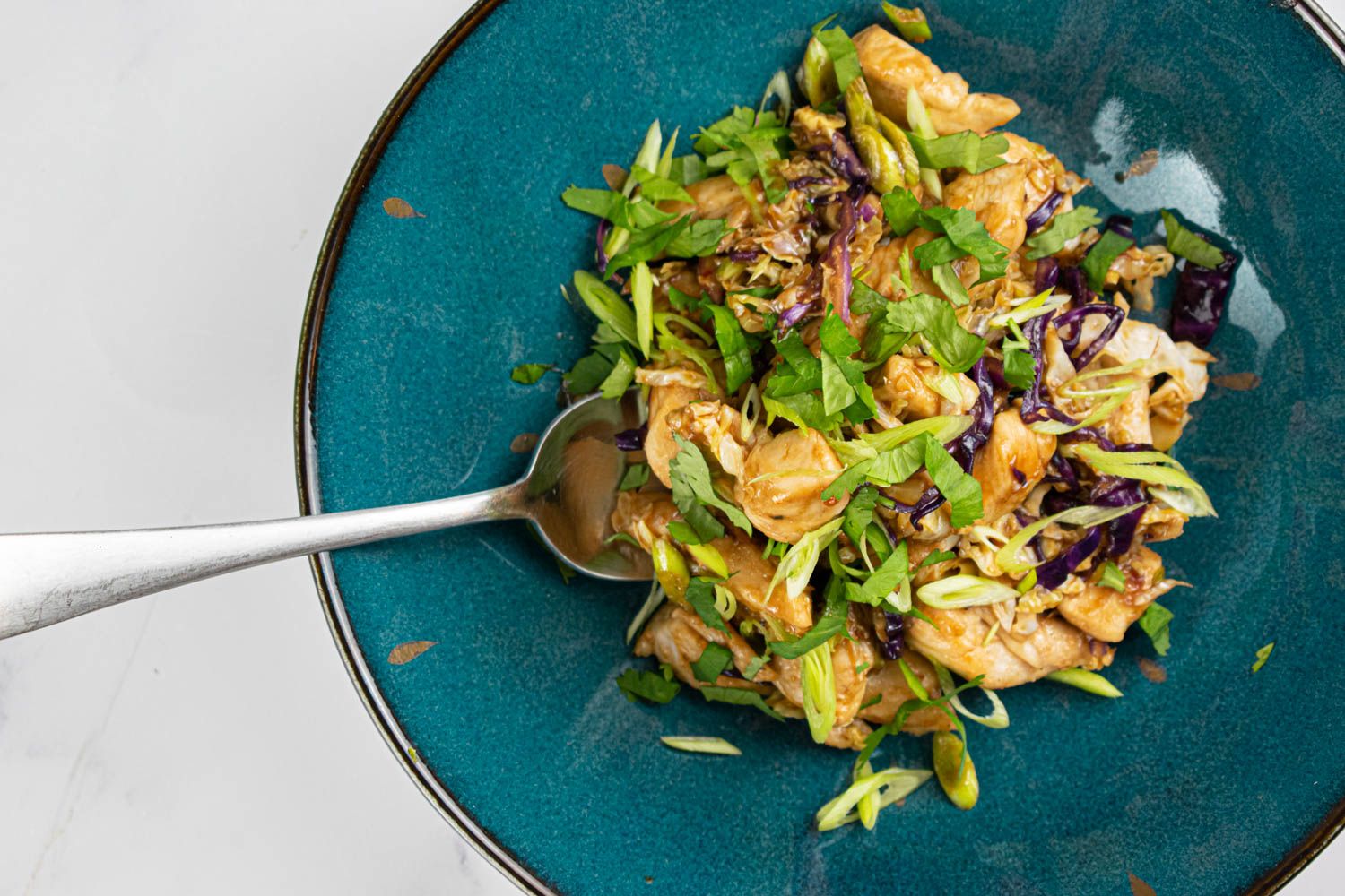 Chinese Moo Shu Chicken and cabbage with green onions in a blue bowl.