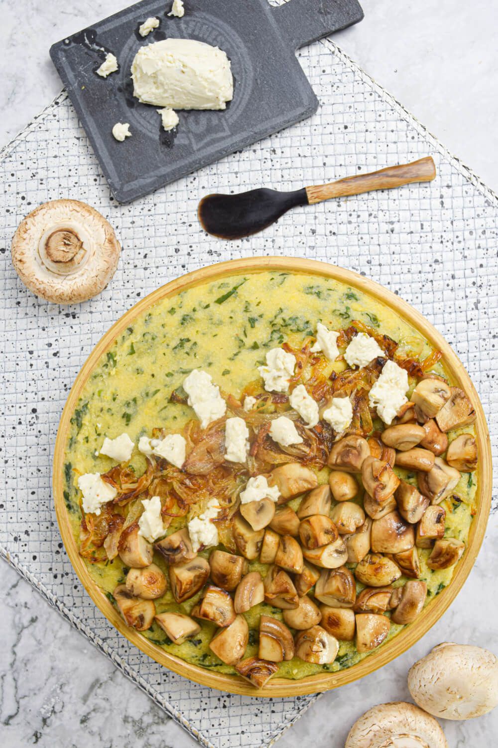 Spinach mushroom polenta with goat cheese on a plate with sauteed onions.