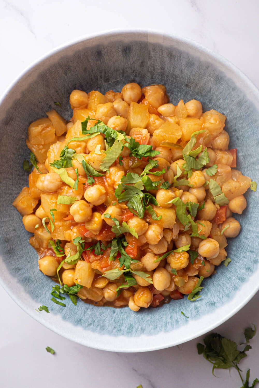 Slow cooker sweet and sour chickpeas with pineapple and red pepper in a blue bowl.