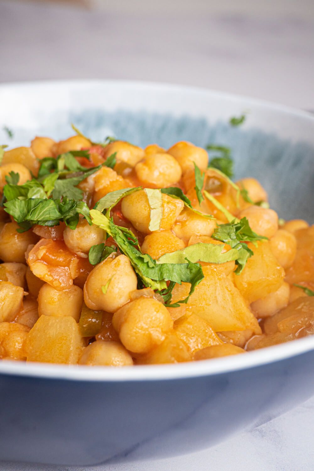 Sweet and sour chickpeas in a bowl with chickpeas, pineapple, red pepper, and cilantro.