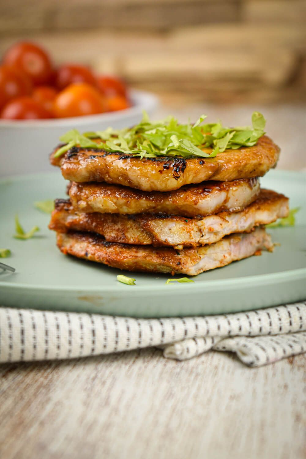 Lean pork chops with homemade spice rub on a plate with cherry tomatoes.