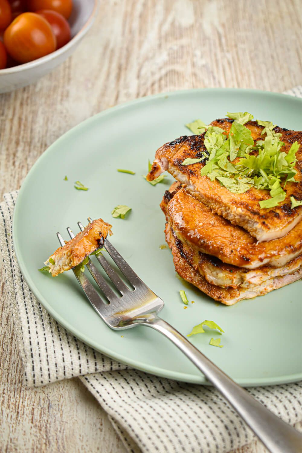 Spice rubbed lean pork chops with parsley being cut by a fork.