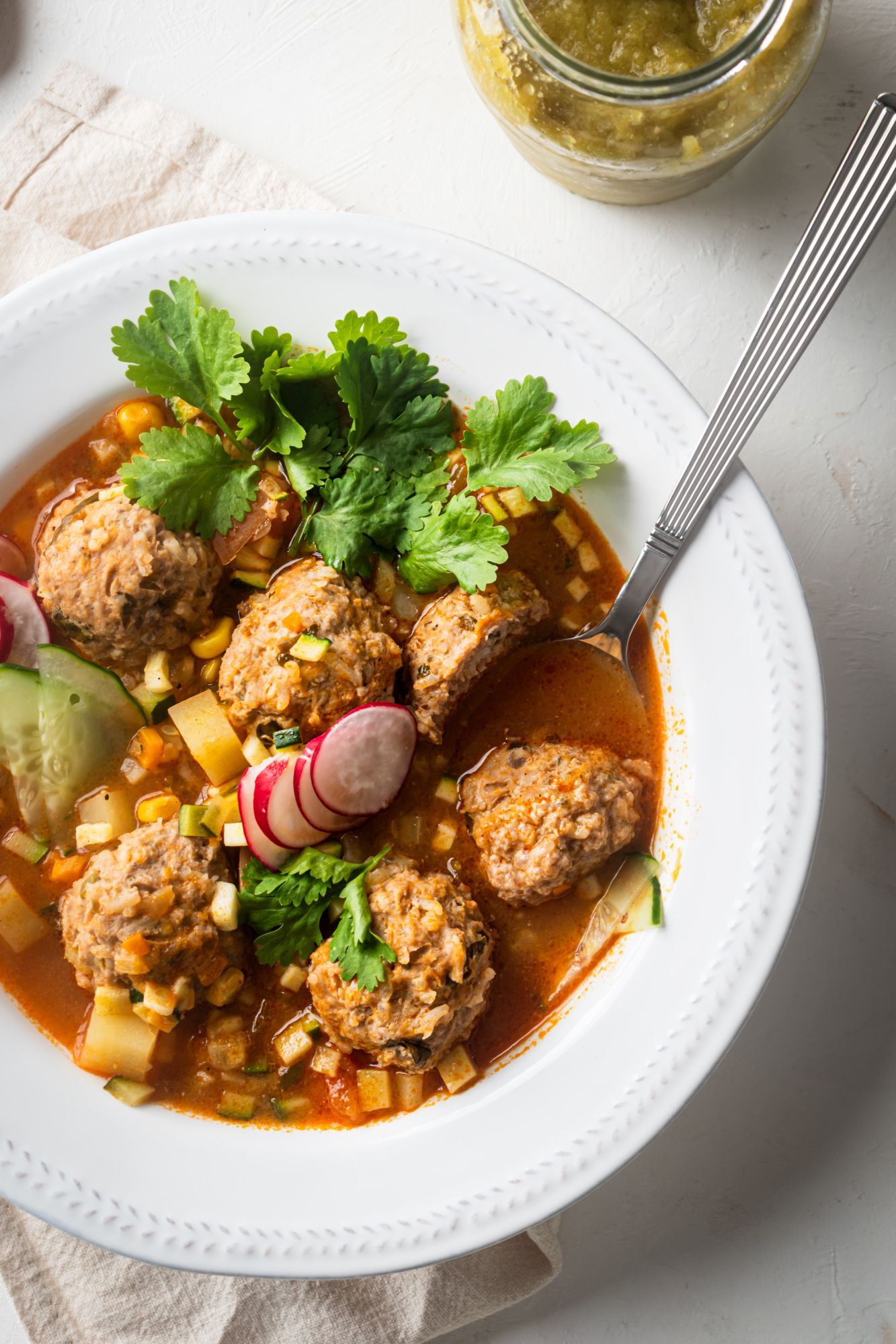 Mexican albondigas soup in a bowl with zucchini, beef meatballs, carrots, corn, and a spicy tomato broth. 