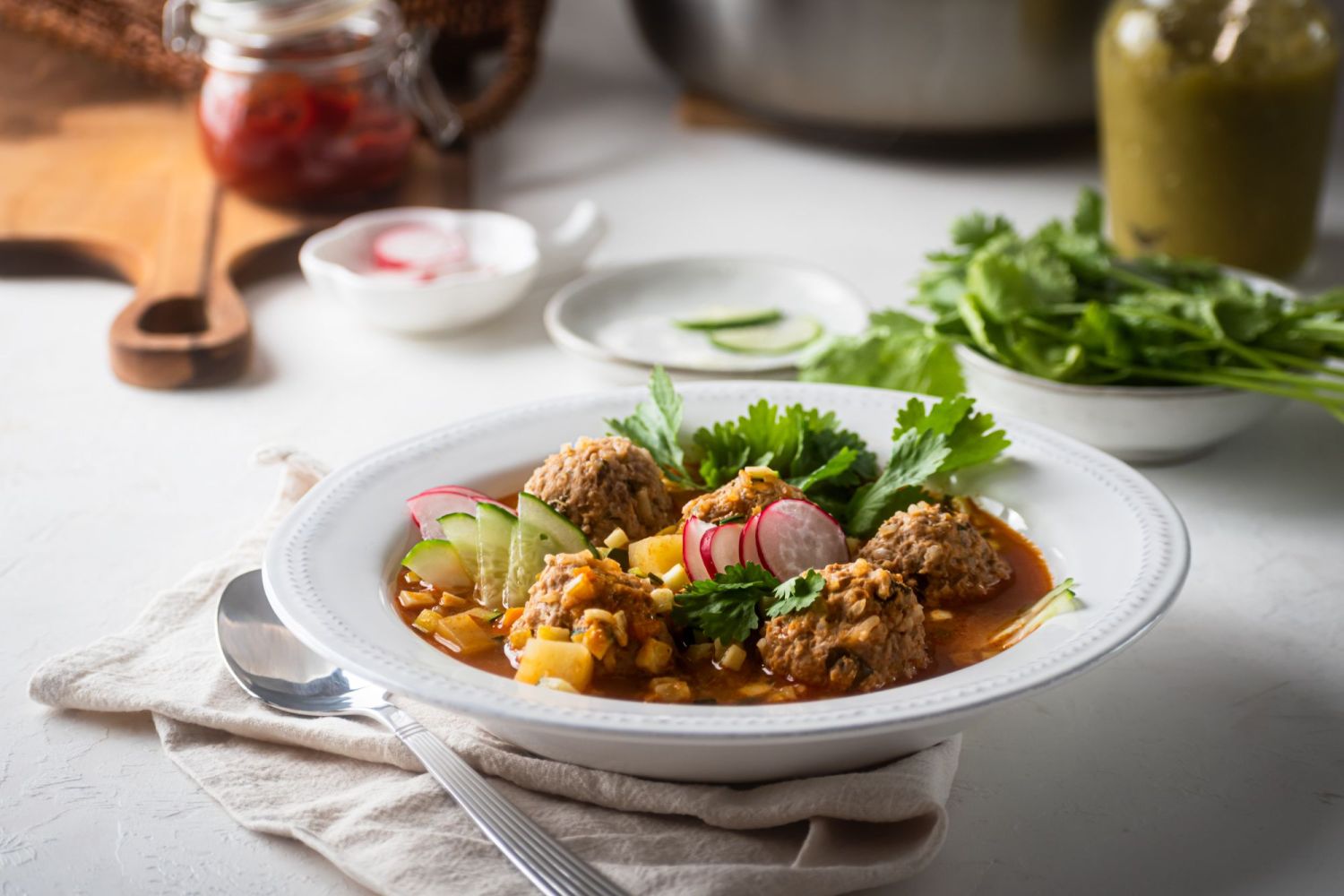 Mexican meatball soup made with ground beef and rice served in a bowl with cilantro and radishes.