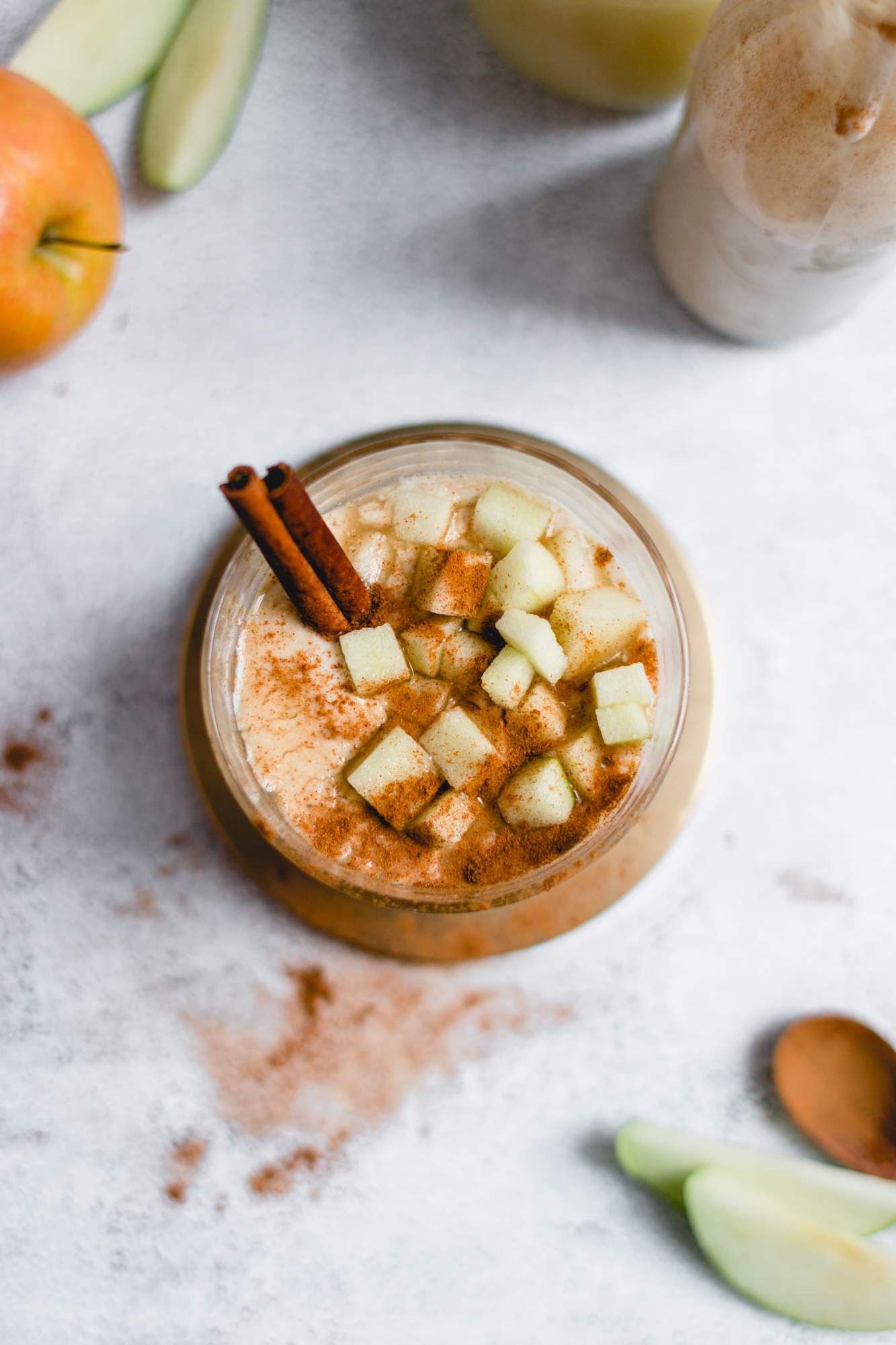 Apple smoothie with bananas in a glass with chopped apples and cinnamon.