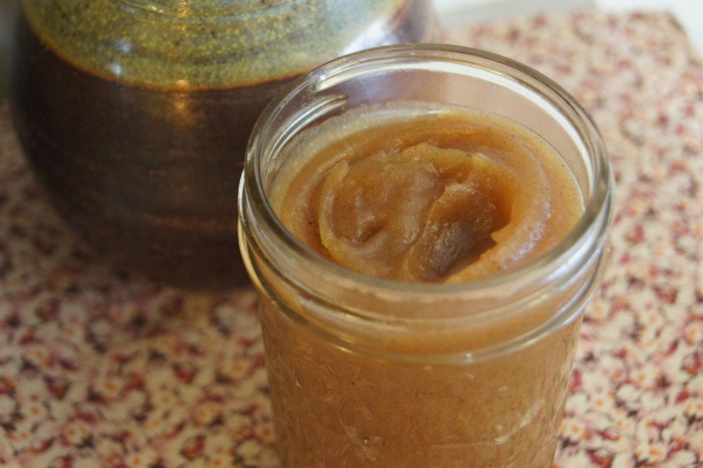 Apple buttter in a glass mason jar with a spoon.