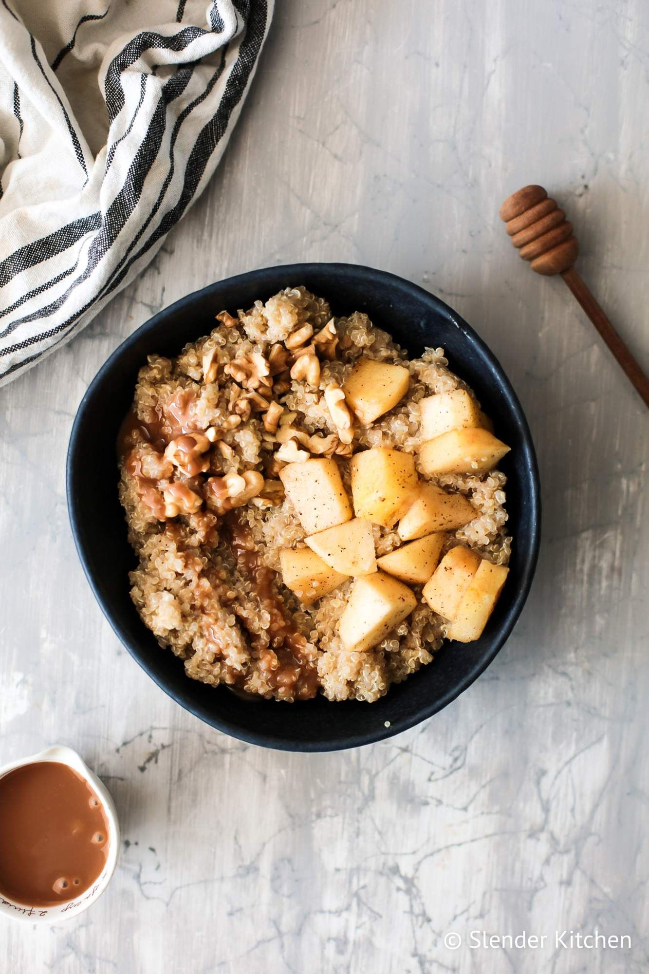 Apple cinnamon quinoa breakfast bowls with walnuts, apples, and caramel sauce in a bowl.